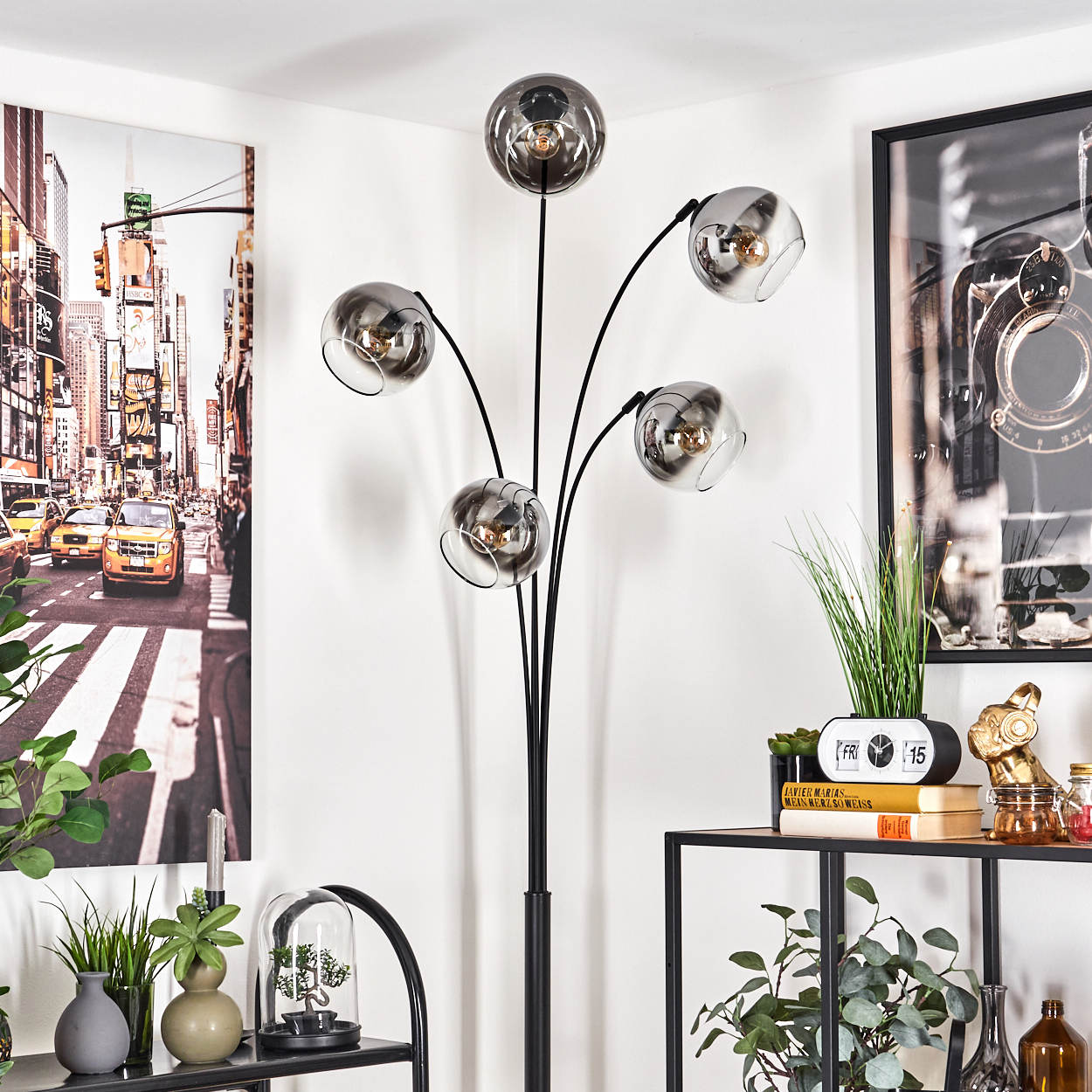 Stehlampe mit fünf Rauchglasschirmen, schwarzem Metallrahmen und einem Bücherregal im Hintergrund.