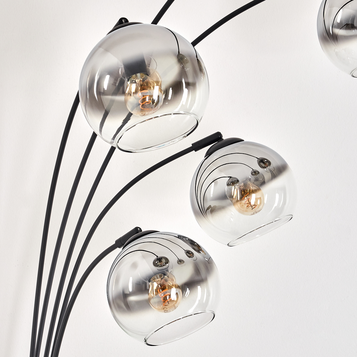 Nahaufnahme eines Satzes kugelförmiger Lampen. Die Lampen haben sichtbare Glühbirnen. Die Lampen haben gebogene Arme.