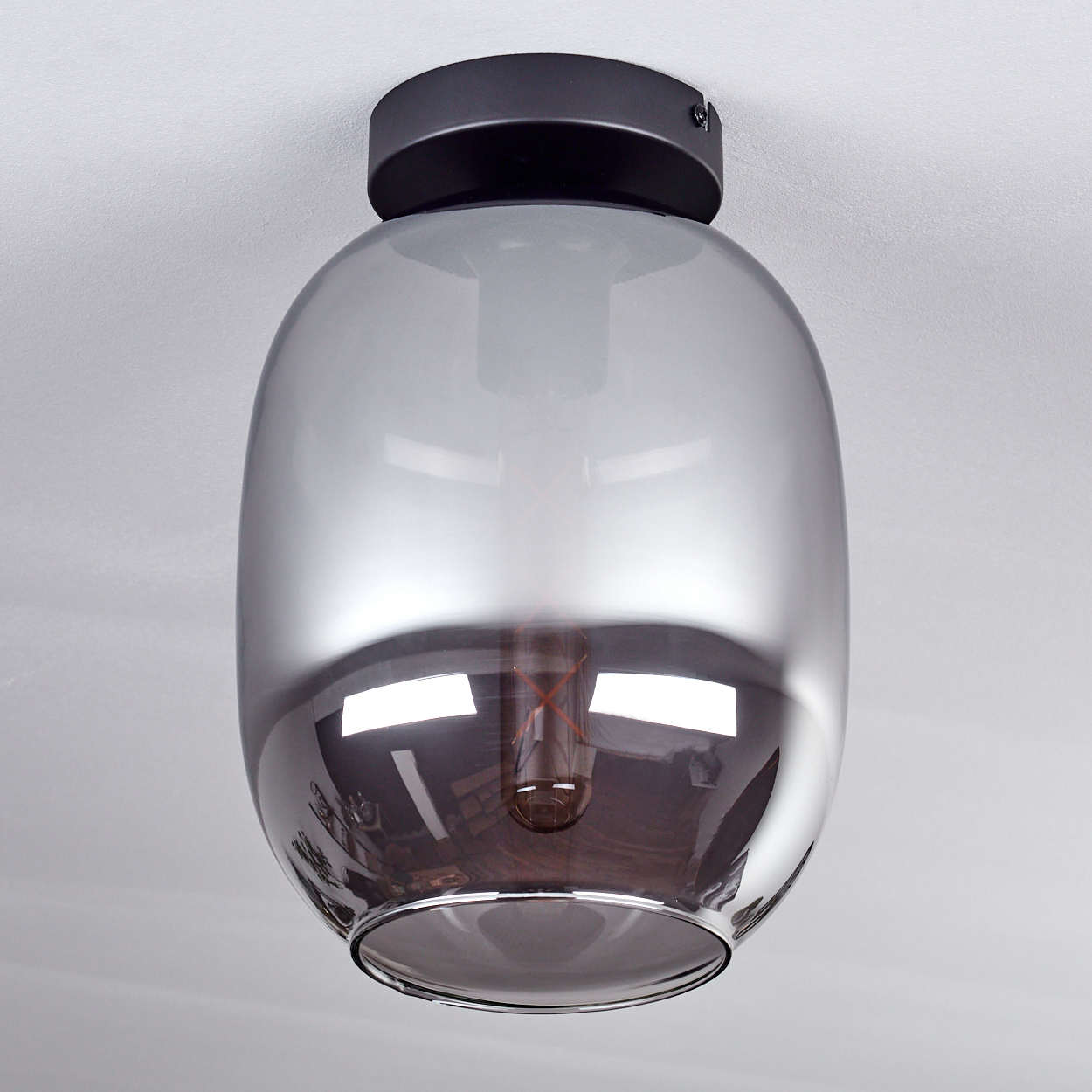 Eine Deckenlampe mit grauem Glasschirm. Die Glühbirne ist sichtbar. Der Hintergrund ist weiß.