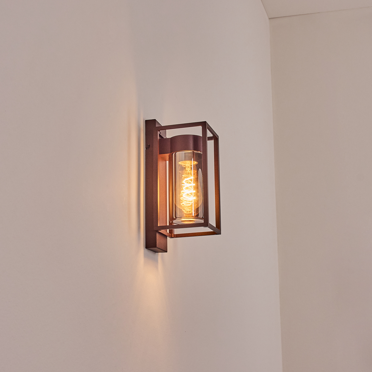 Eine braune Wandleuchte mit rechteckigem Rahmen. Sie ist an einer weißen Wand befestigt.