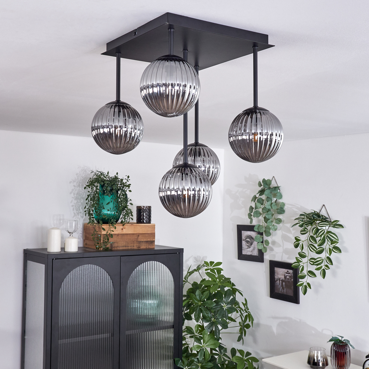 Eine Deckenlampe mit 5 silbernen Kugelschirmen, schwarzem Rahmen. Die Szene beinhaltet weitere Dekorationen und Möbel.