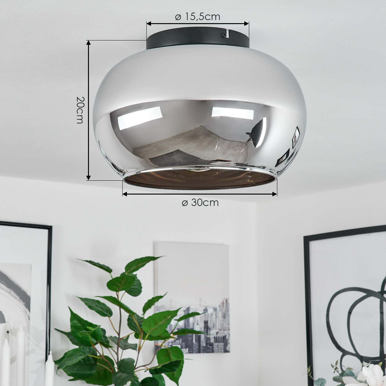 Eine verchromte Deckenlampe mit Abmessungen. Im Hintergrund sind eine Pflanze und gerahmte Bilder zu sehen.