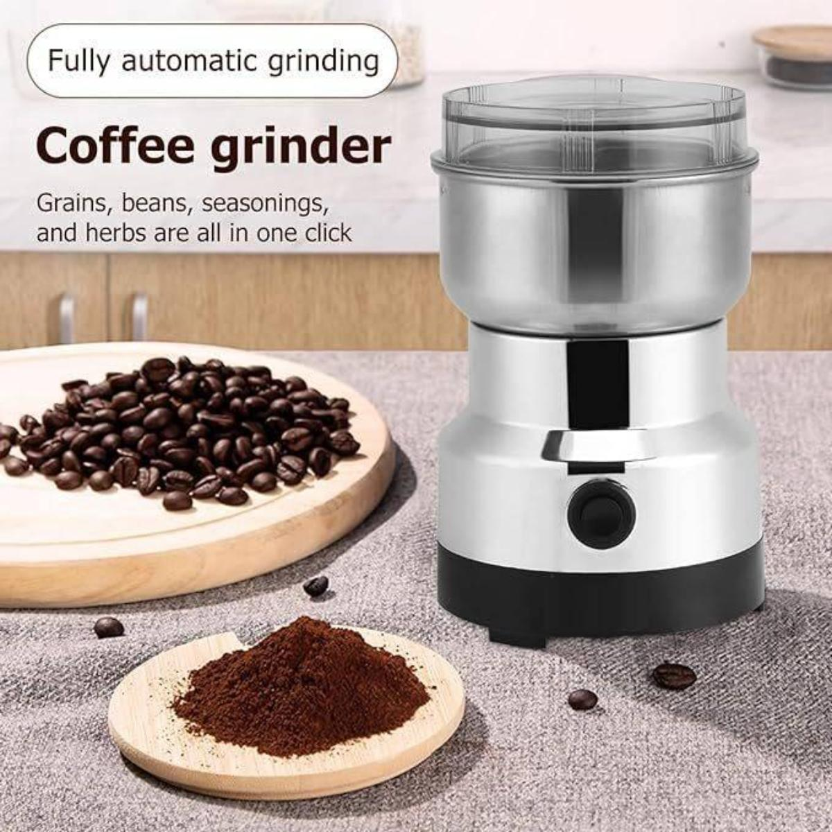 Eine silberne Kaffeemühle mit Kaffeebohnen, gemahlenem Kaffee und Text. Die Mühle steht auf einer grauen Oberfläche.