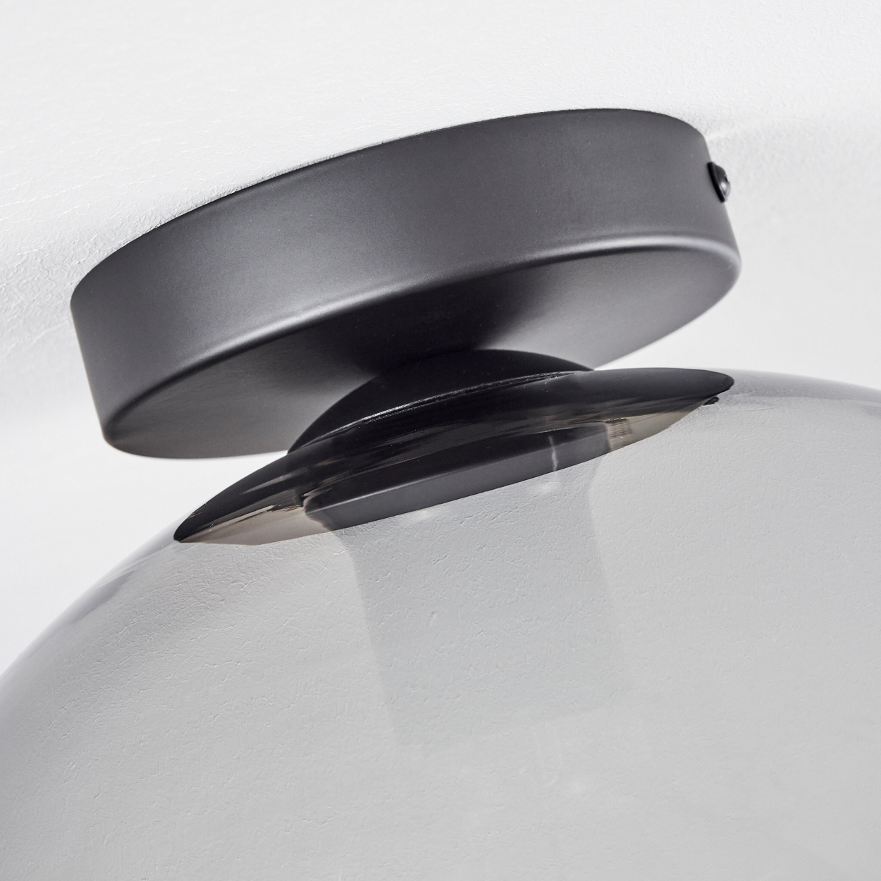 Nahaufnahme der Deckenhalterung einer Lampe. Die Halterung ist schwarz und grau.