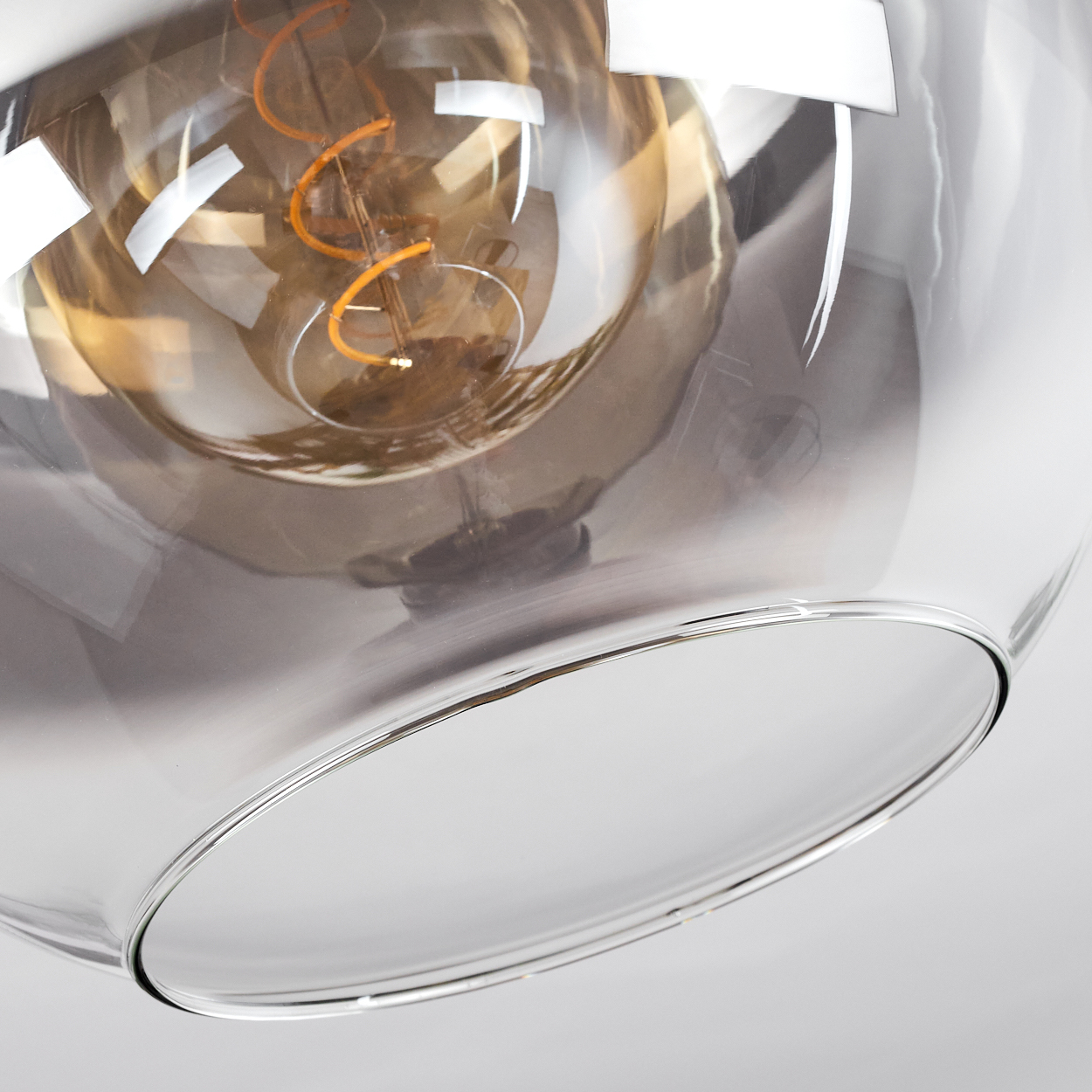 Nahaufnahme eines runden Glasschirms mit einer Wendelglühbirne im Inneren.