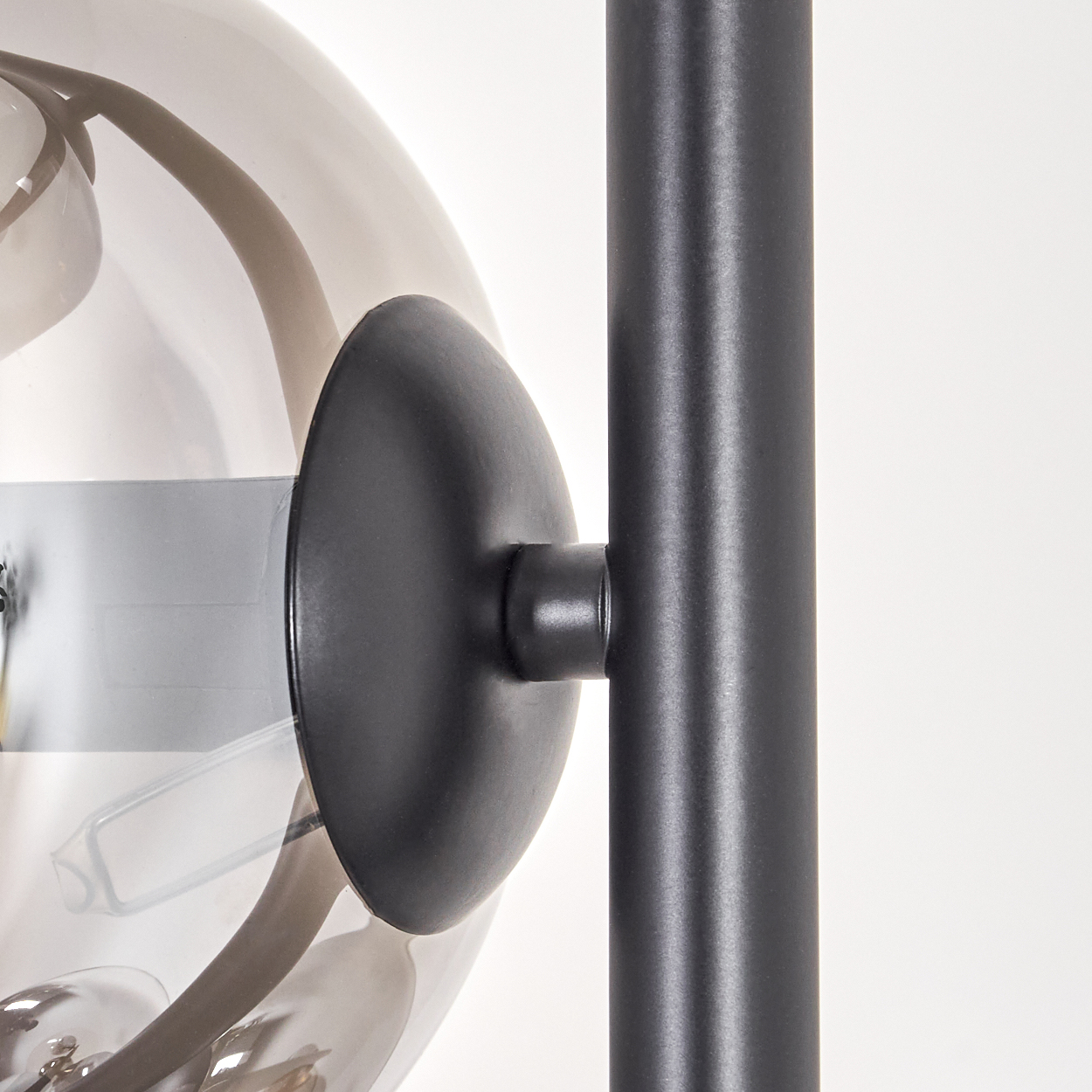 Nahaufnahme einer Stehlampe mit schwarzem Pfosten, Glaskugel und schwarzer Halterung.