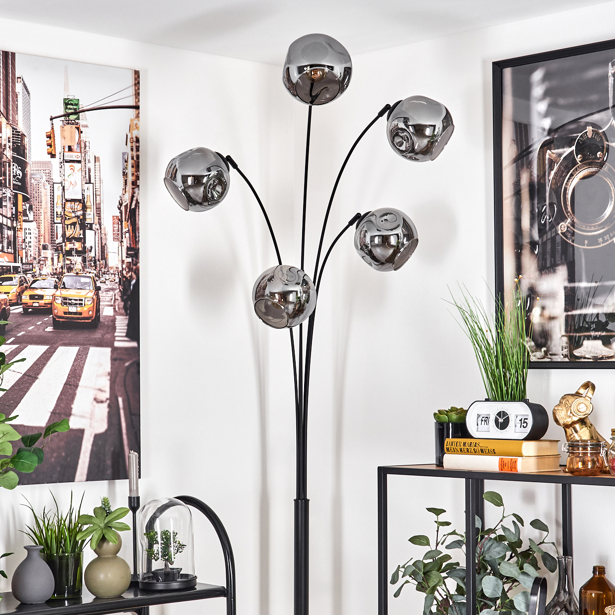 Eine Stehlampe mit Chromkugelschirmen steht in einem Raum mit einem Stadtbildgemälde an der Wand.