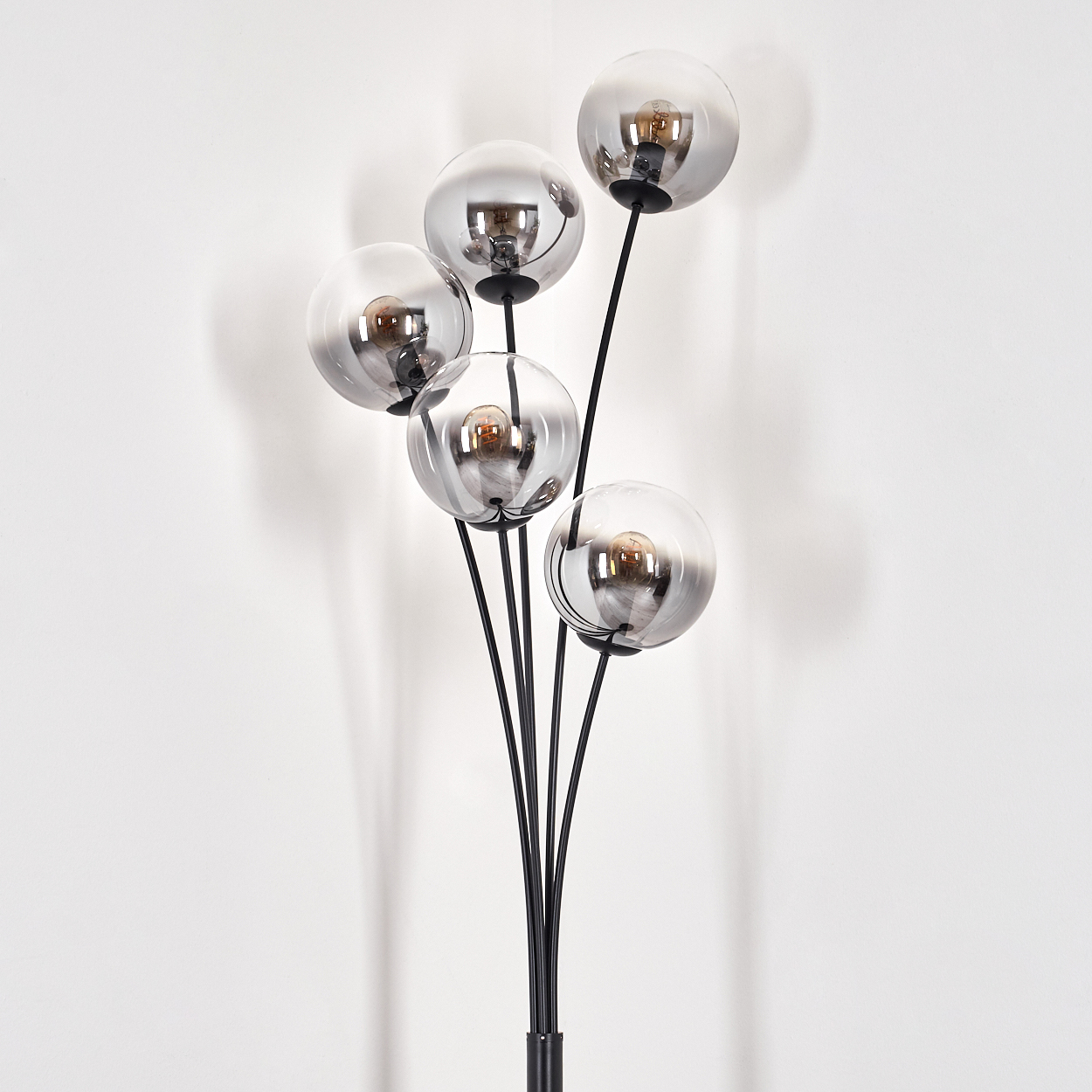 Eine schwarze Stehlampe mit fünf Glaskugelschirmen. Die Schirme sind reflektierend und der Hintergrund ist weiß.