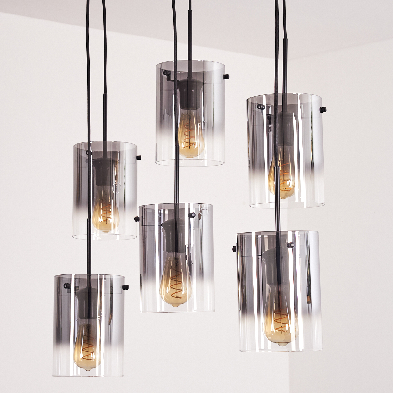 Nahaufnahme von Hängelampen mit Glaszylinderschirmen und Glühbirnen. Die Lampen sind von oben.