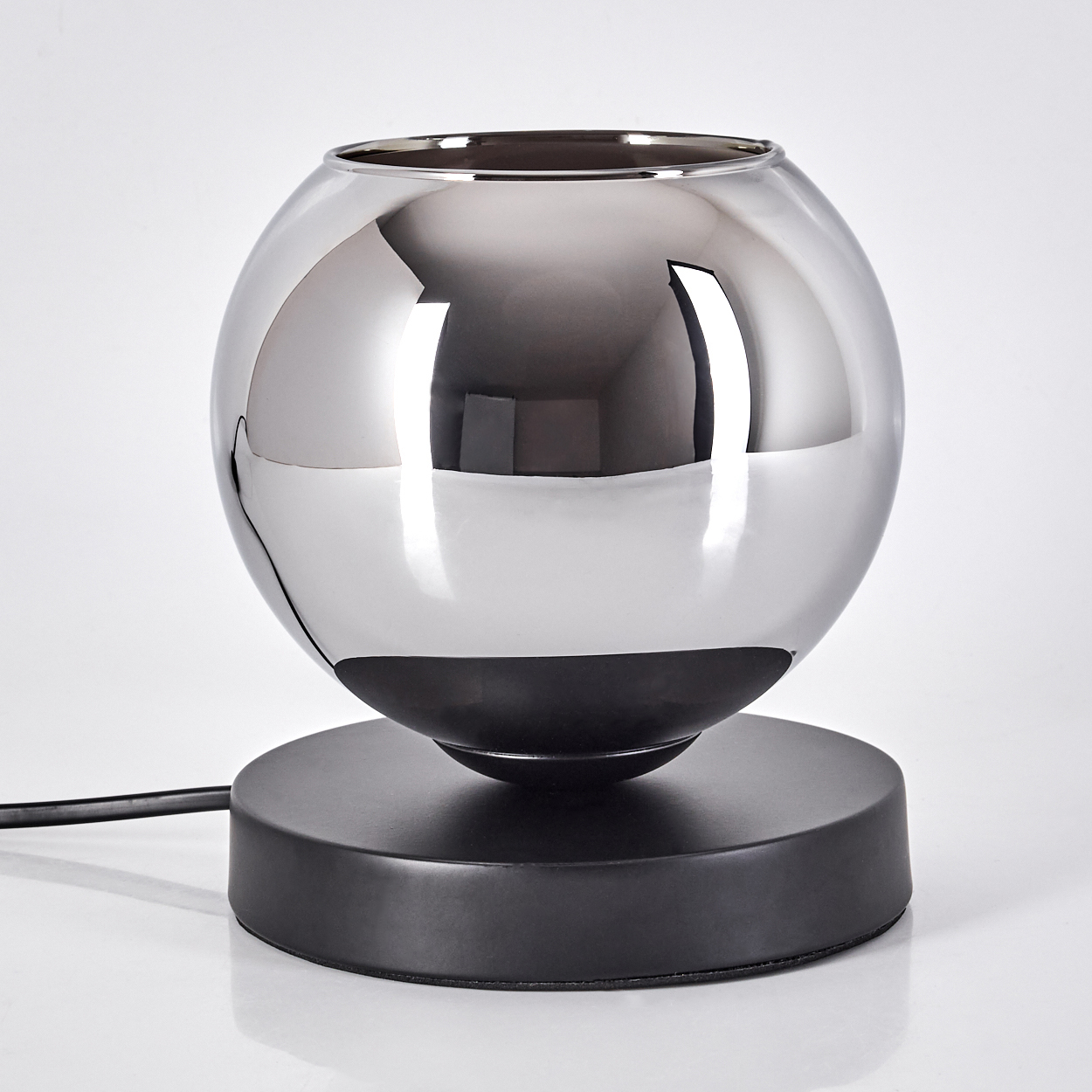 Eine Kugellampe mit schwarzem Sockel, die die Umgebung reflektiert. Die Lampe steht vor weißem Hintergrund.