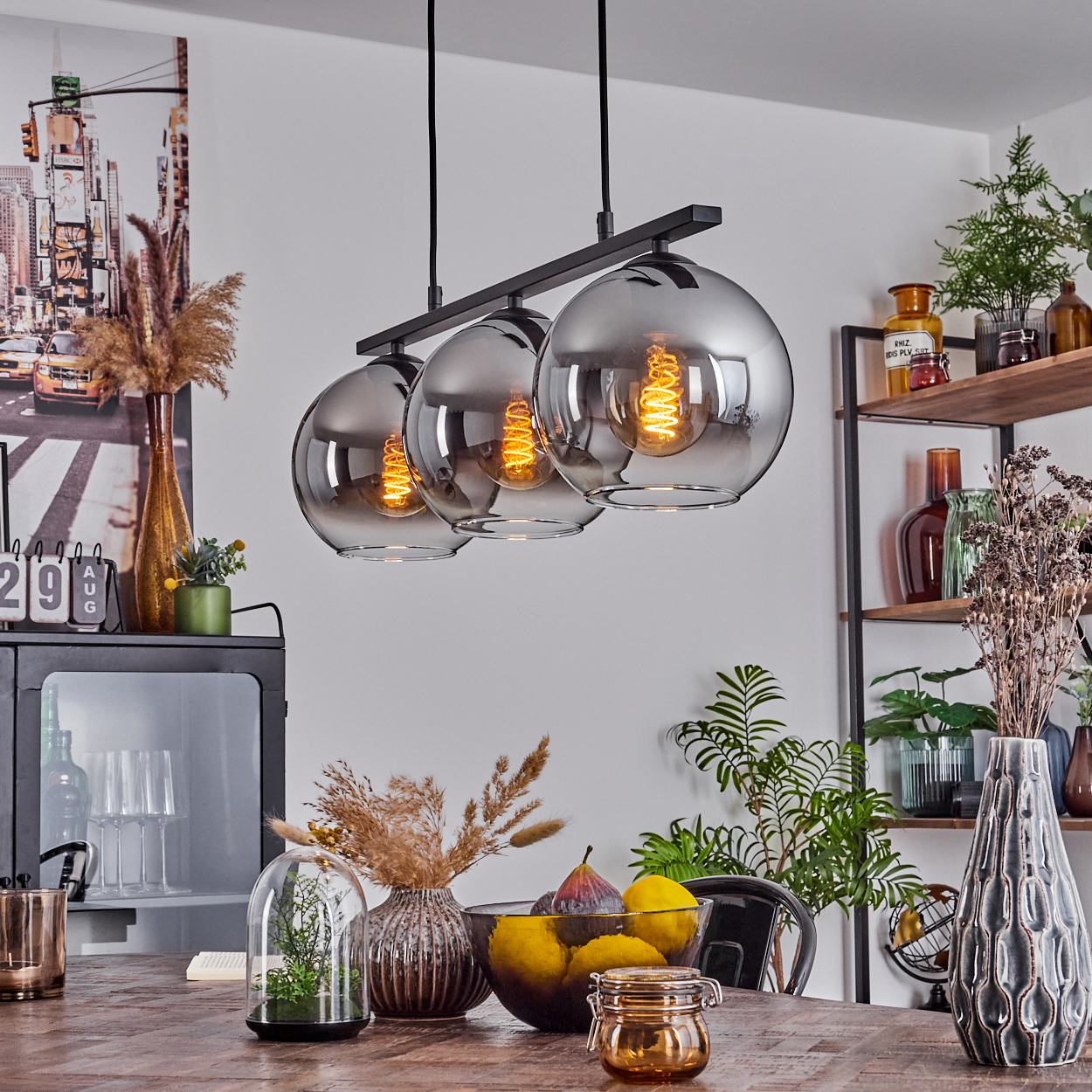 Drei Pendelleuchten mit silbernen Kugeln, ein Holztisch und Dekorationselemente.