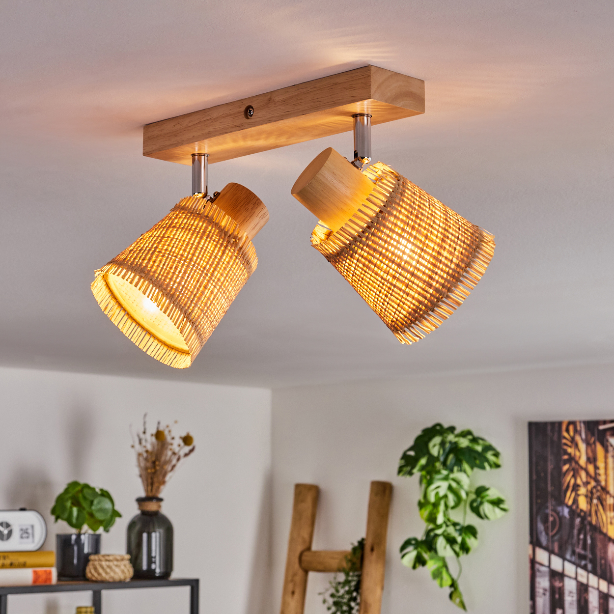 Eine Deckenlampe mit zwei gewebten Schirmen, die in einer Raumeinstellung beleuchtet werden, mit einer Leiter und Dekoration.
