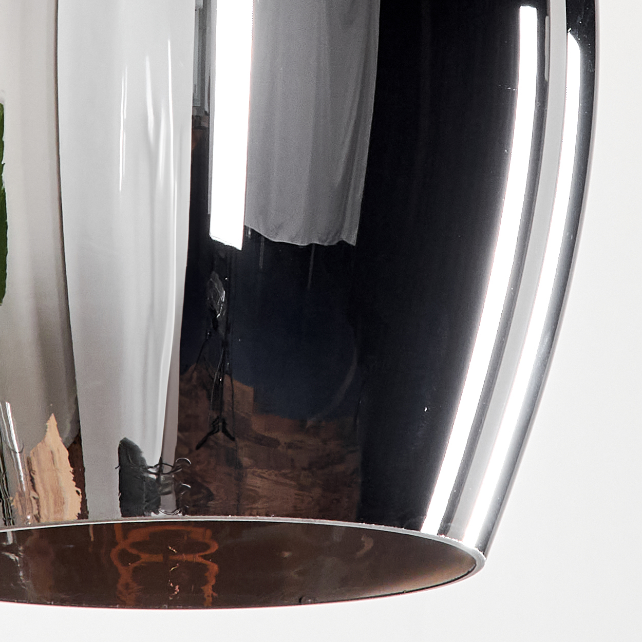 Nahaufnahme einer Chrom-Pendelleuchte. Die Lampe ist glänzend und metallisch.