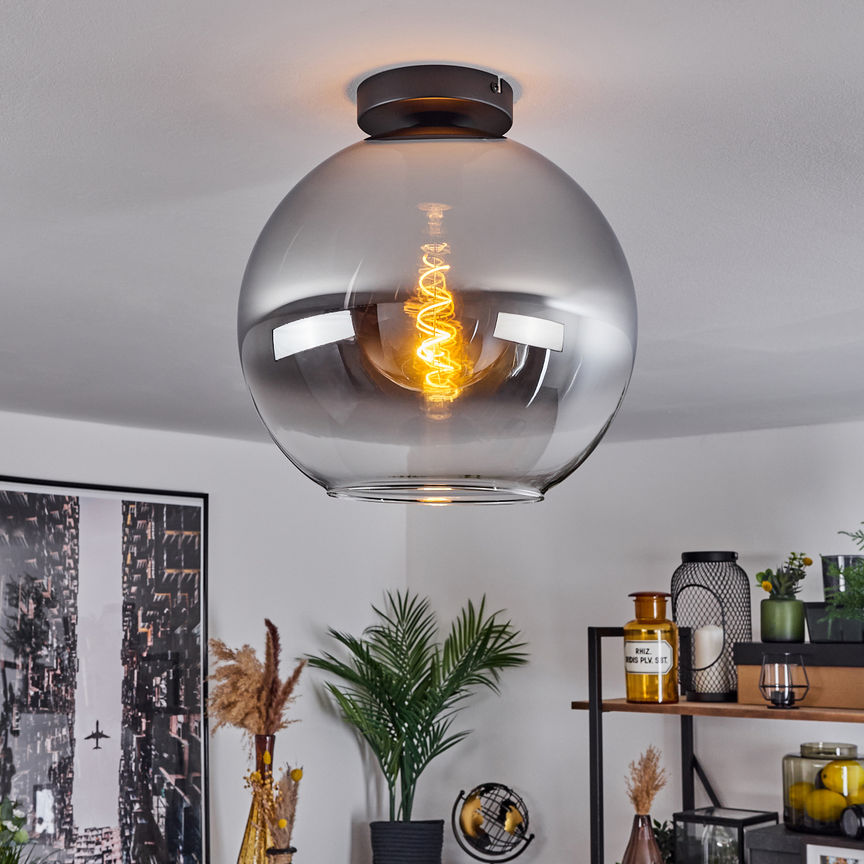 Eine Deckenleuchte mit einem großen, klaren, kugelförmigen Glasschirm und einer sichtbaren Glühbirne, an einer Decke montiert.