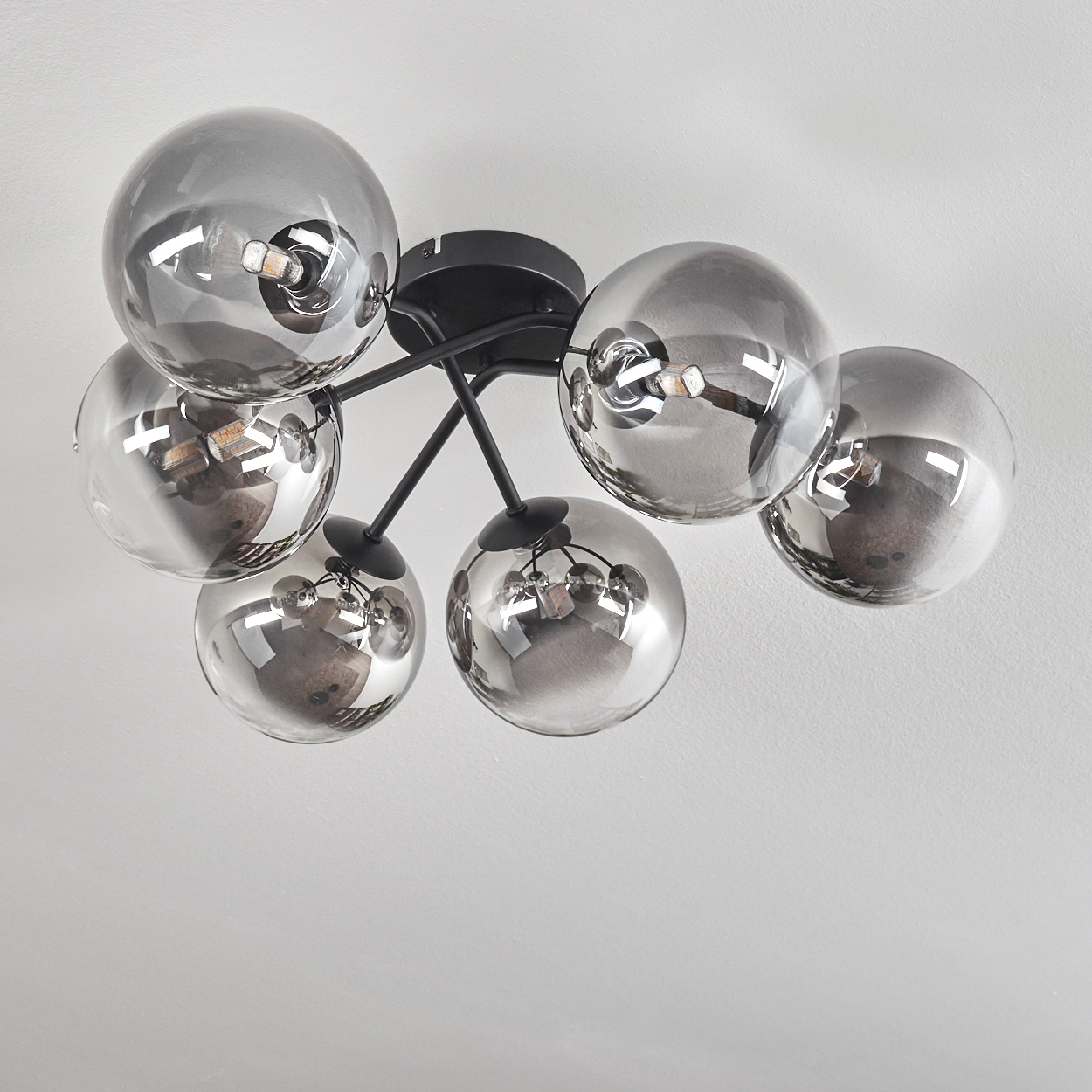 Eine Deckenleuchte mit sechs Glaskugeln, angeordnet in einem Cluster. Die Kugeln sind reflektierend, an einer Decke montiert.