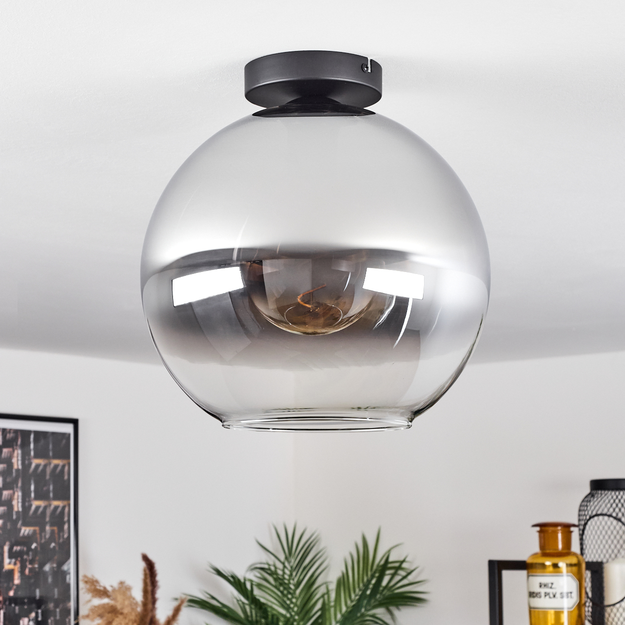 Eine Deckenleuchte mit silberfarbener Glühbirne, die in Glas eingeschlossen ist, und schwarzem Sockel.