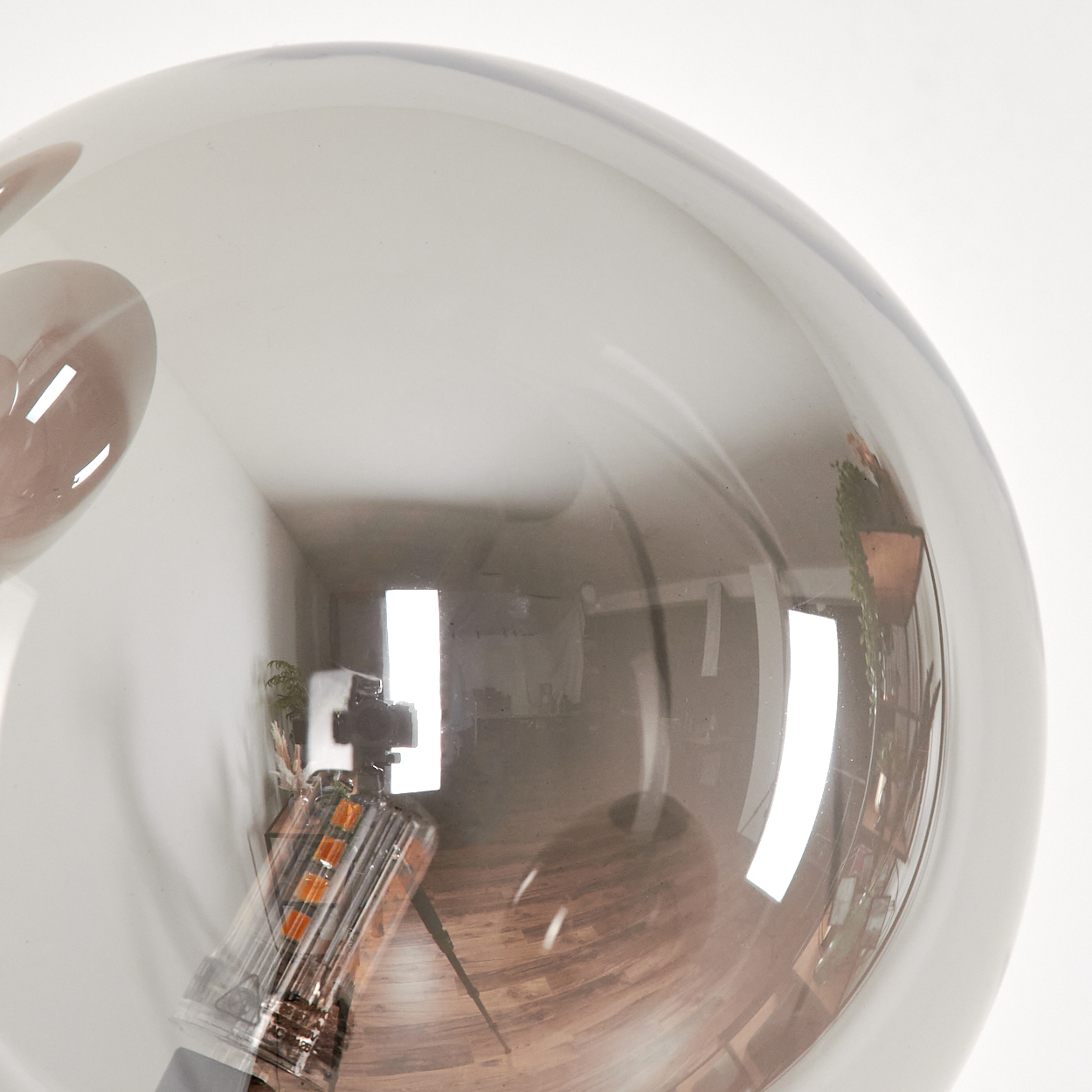 Nahaufnahme einer Glaskugel mit einer Glühbirne im Inneren. Das Innere wird reflektiert.