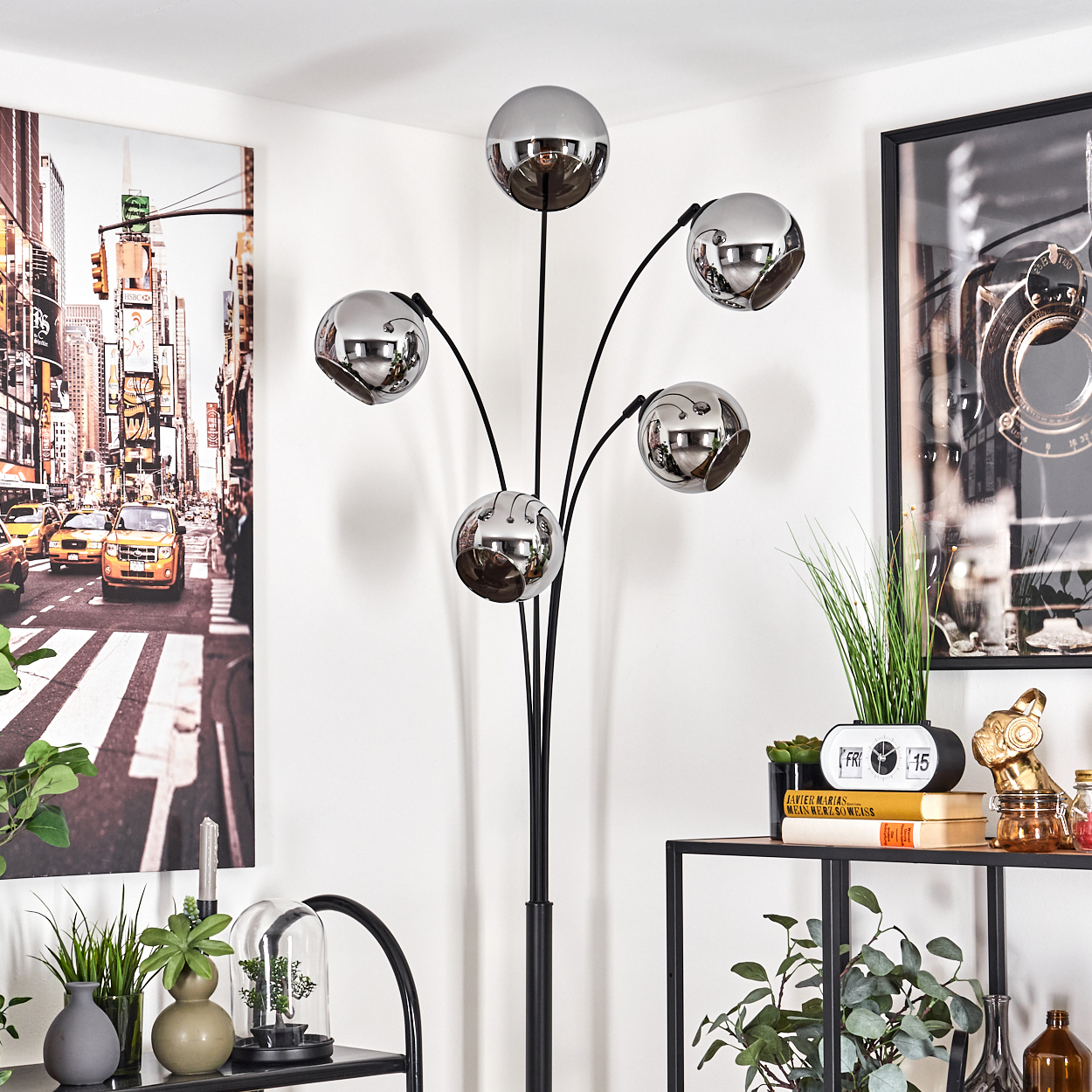 Eine Stehlampe mit fünf Chromkugelleuchten steht in der Nähe von Kunstwerken und Dekoration.