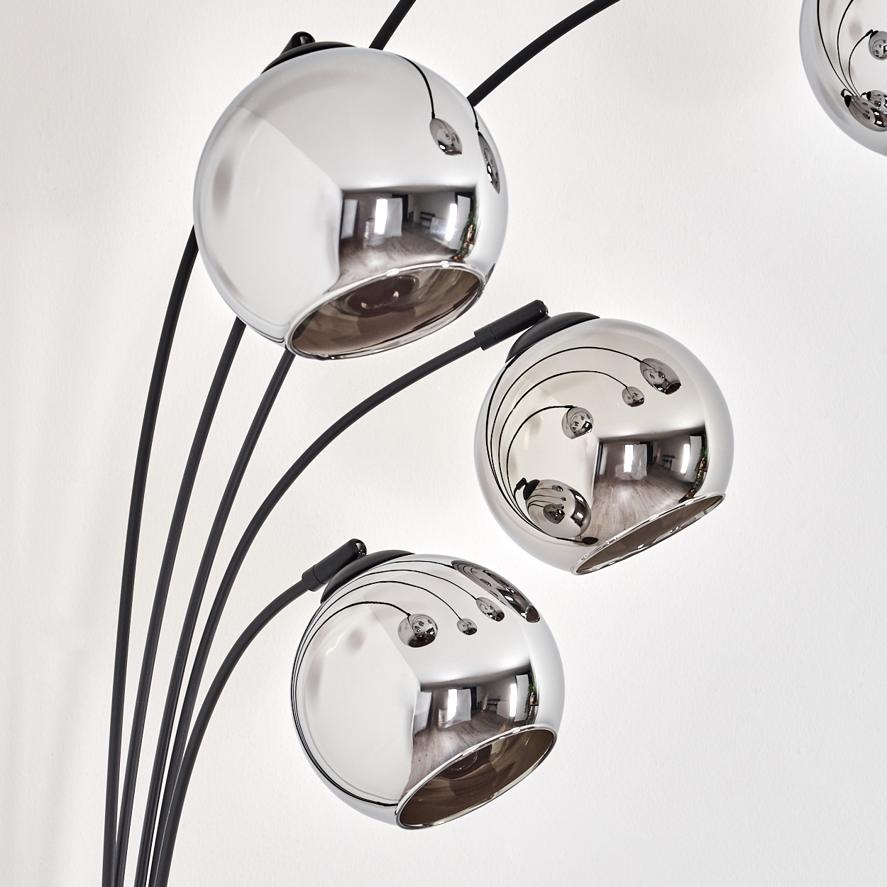 Nahaufnahme einer Stehlampe mit drei reflektierenden Kugeln. Die Kugeln reflektieren eine weiße Wand.