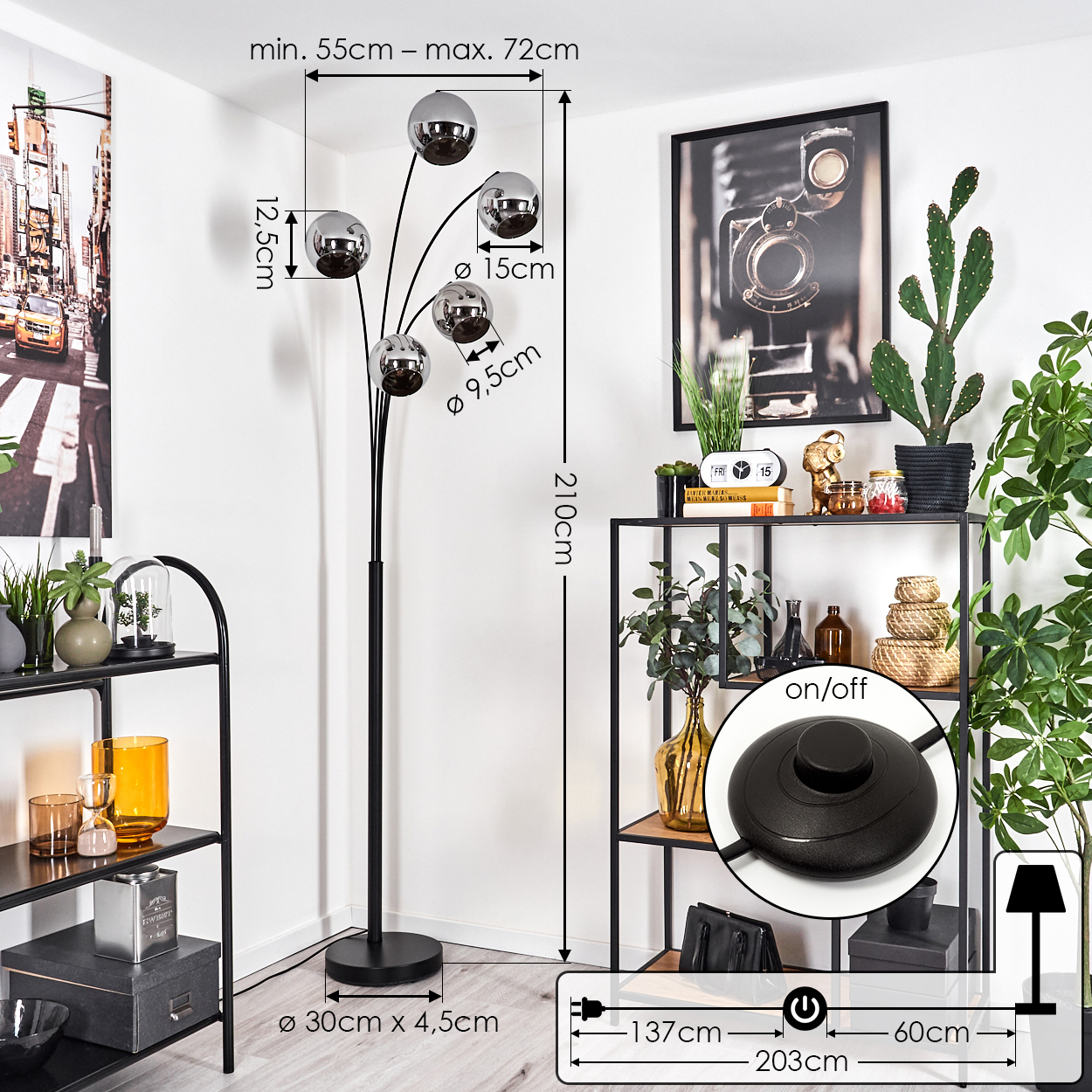 Eine Stehlampe mit Maßangaben. Sie hat fünf reflektierende Kugeln und einen Fußschalter, in der Nähe eines Regals mit Gegenständen.
