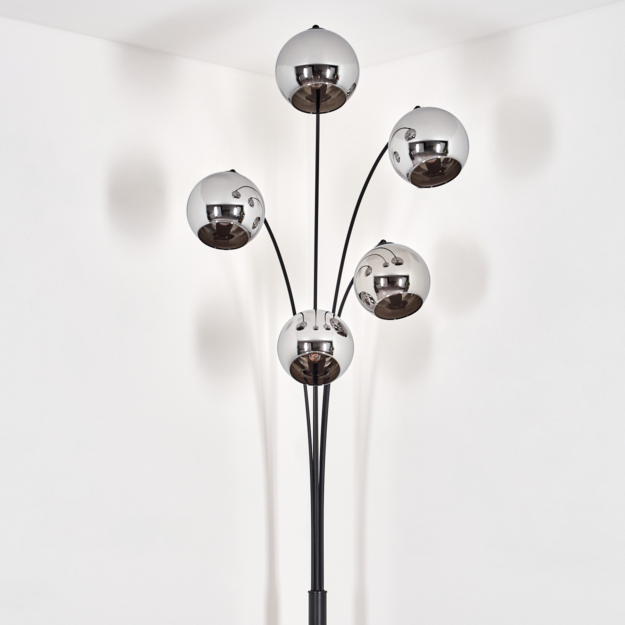 Eine Stehlampe mit fünf reflektierenden Kugeln. Die Lampe steht in der Ecke eines weißen Raumes.