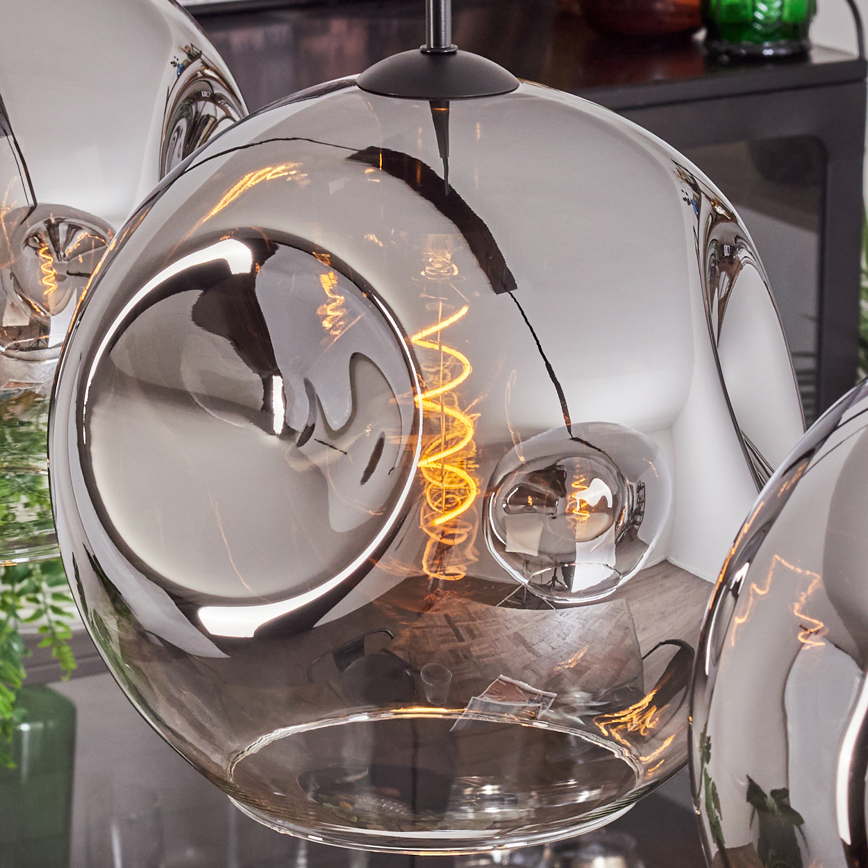 Nahaufnahme einer grauen Glas-Pendelleuchte mit sichtbarer Glühbirne. Der Glühfaden der Glühbirne ist deutlich sichtbar.