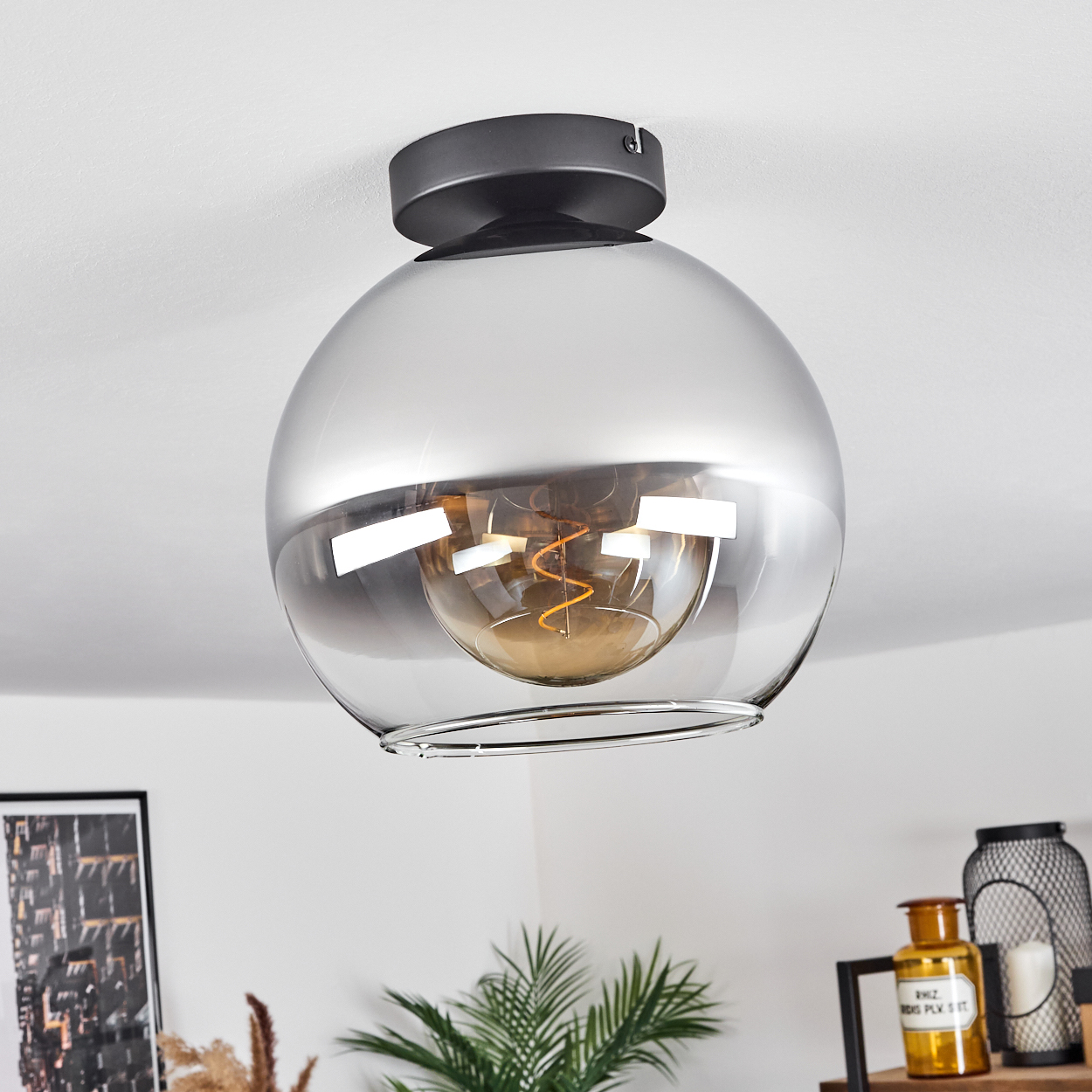 Eine Deckenleuchte mit einer silber verspiegelten Kugel und einer Edison-Glühbirne. Die Leuchte ist an der Decke befestigt.