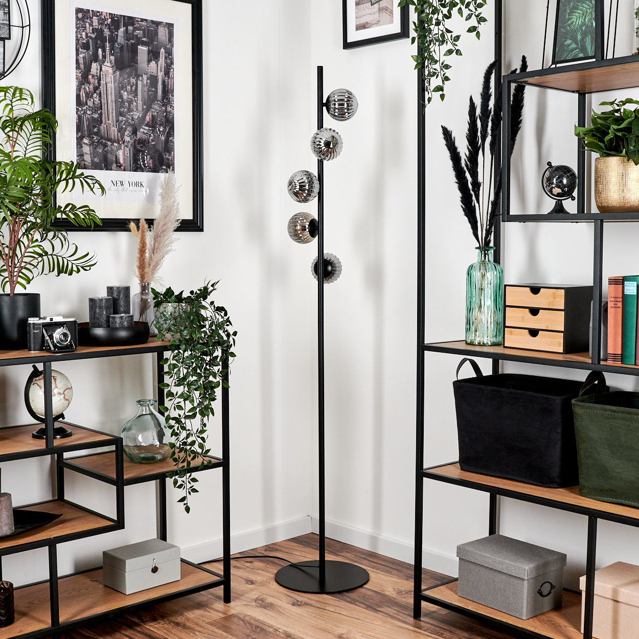 Wohnzimmer-Setup mit Stehlampe, Regalen mit Dekor und New York-Bild.