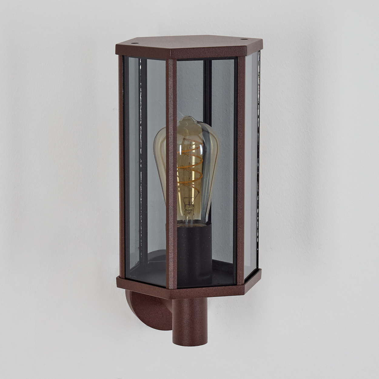 Nahaufnahme einer wandmontierten Außenleuchte mit sechseckigem Glasschirm.