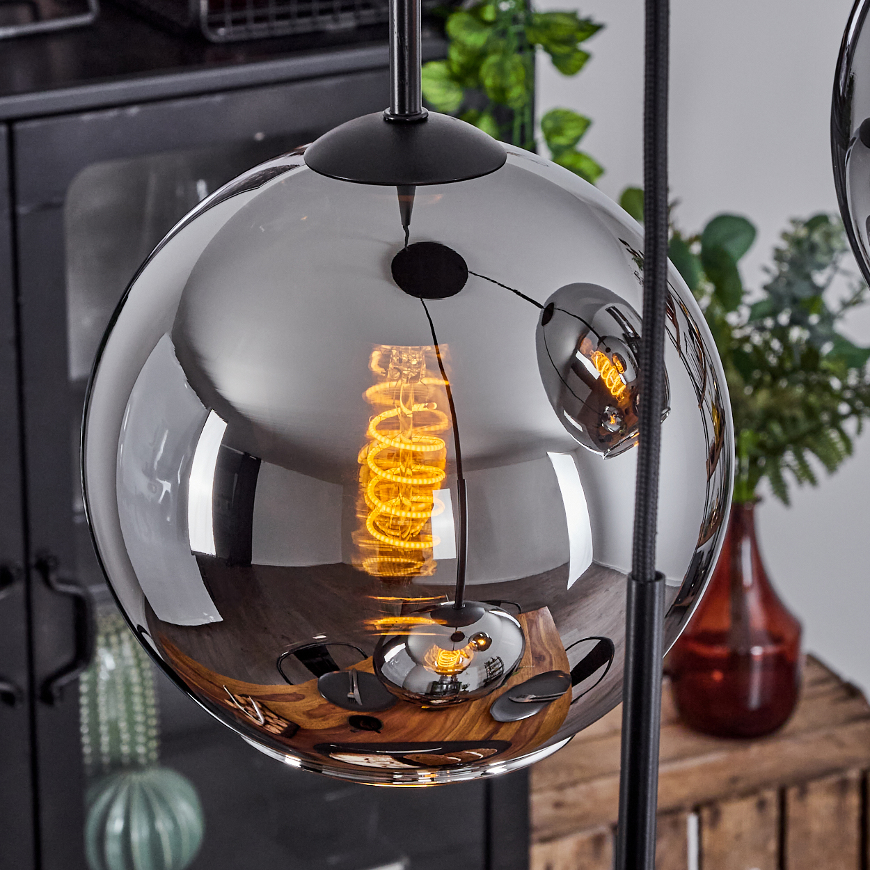 Nahaufnahme einer kugelförmigen Lampe mit sichtbarer Glühbirne, die die Details des Raumes widerspiegelt.