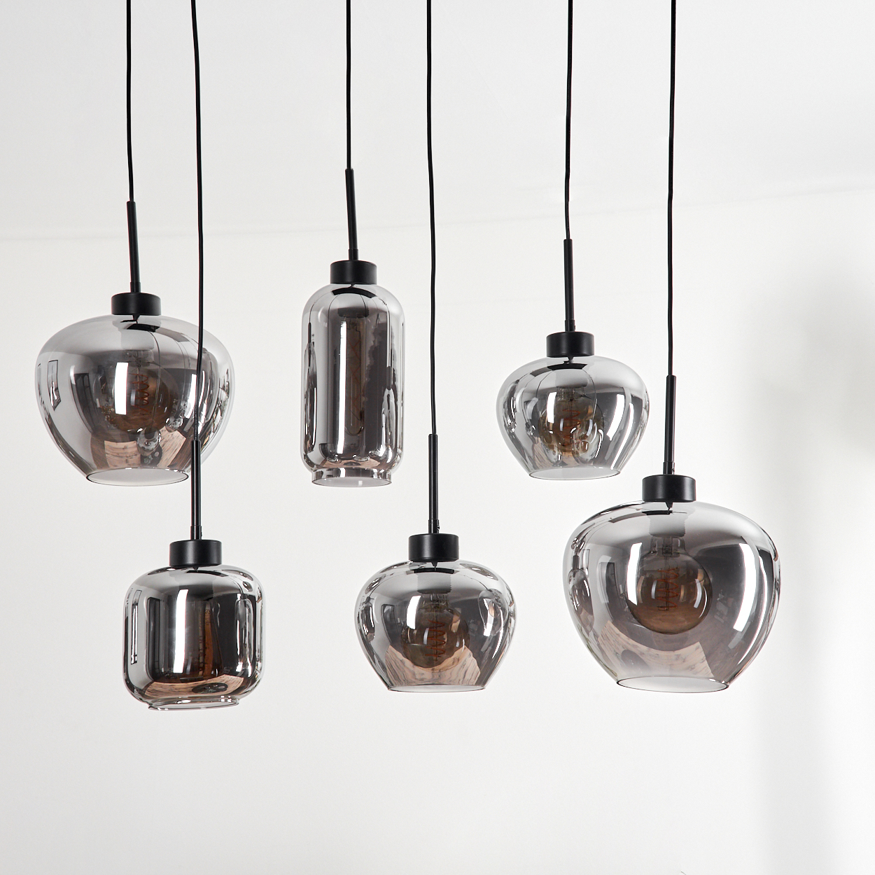 Sechs Pendelleuchten mit verspiegelten Glasschirmen. Die Leuchten hängen von der Decke. Weißer Hintergrund.