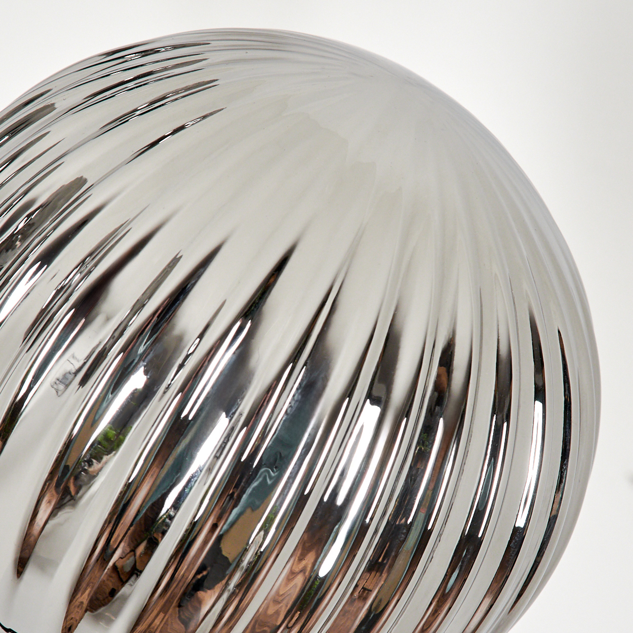 Nahaufnahme eines geriffelten, silbernen Glasschirms. Reflektiertes Licht erzeugt vertikale Linien und hebt die Textur hervor.