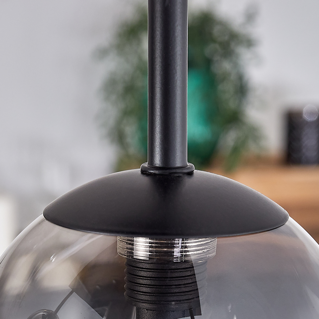 Nahaufnahme einer Deckenlampe. Zeigt den schwarzen Sockel und die rauchige Glaskugel.