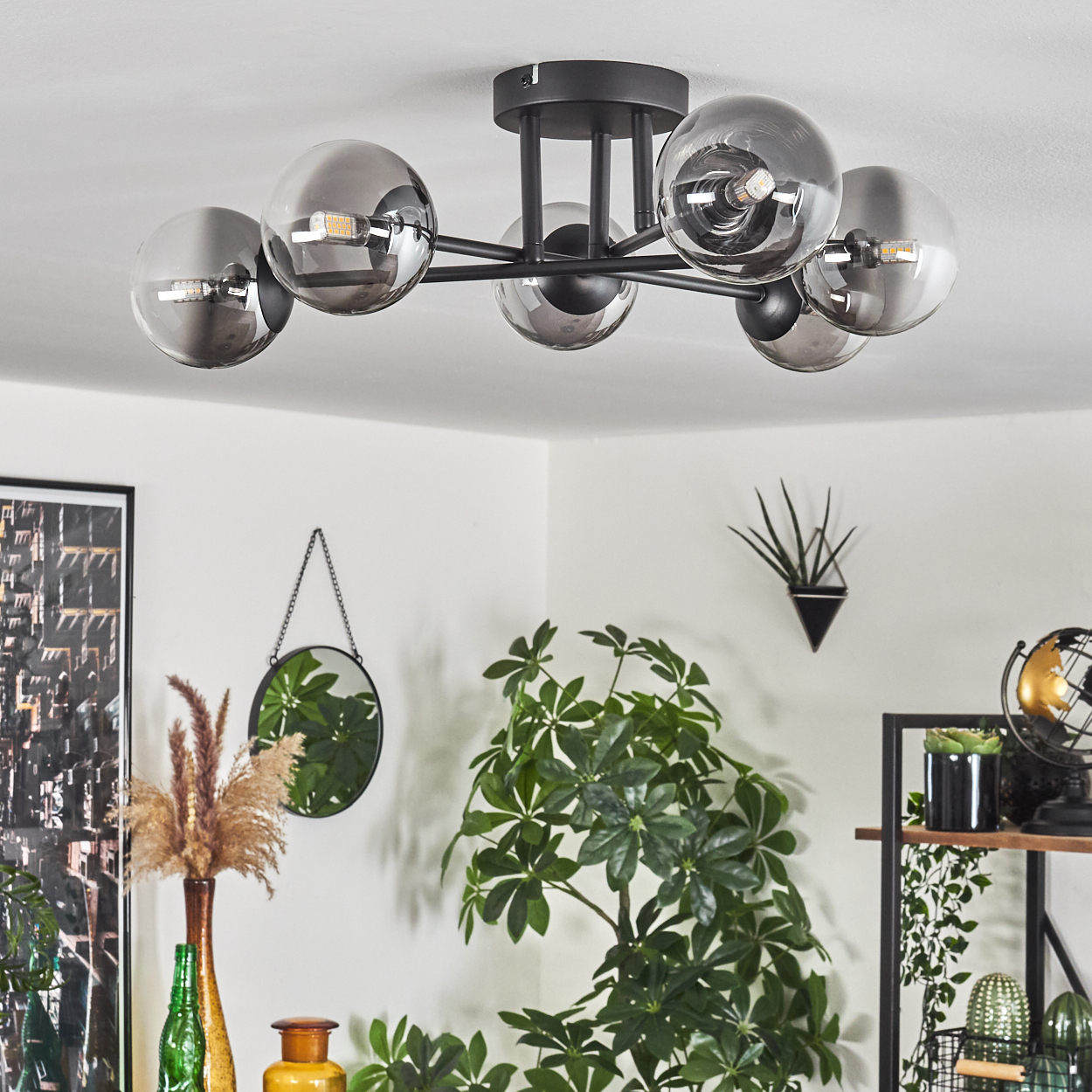 Ein Essbereich mit Deckenlampe. Links Pflanze und Spiegel, rechts Globus. Der Raum ist hell.
