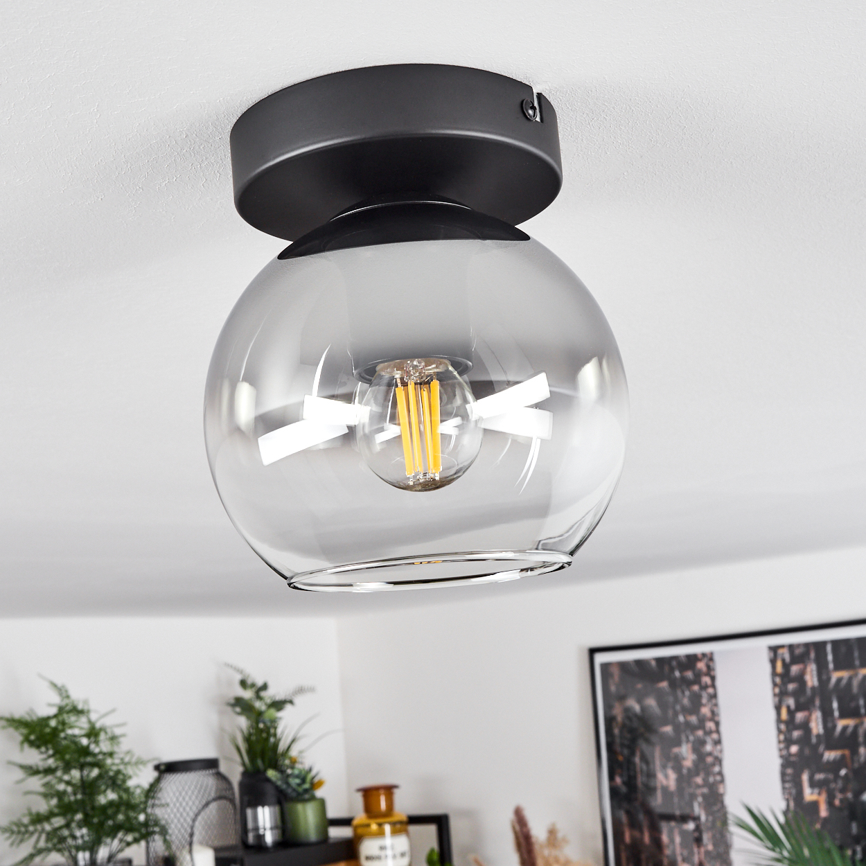 Deckenleuchte mit einem verspiegelten Kugelschirm und einer Edison-Glühbirne. Sie hängt von der Decke.