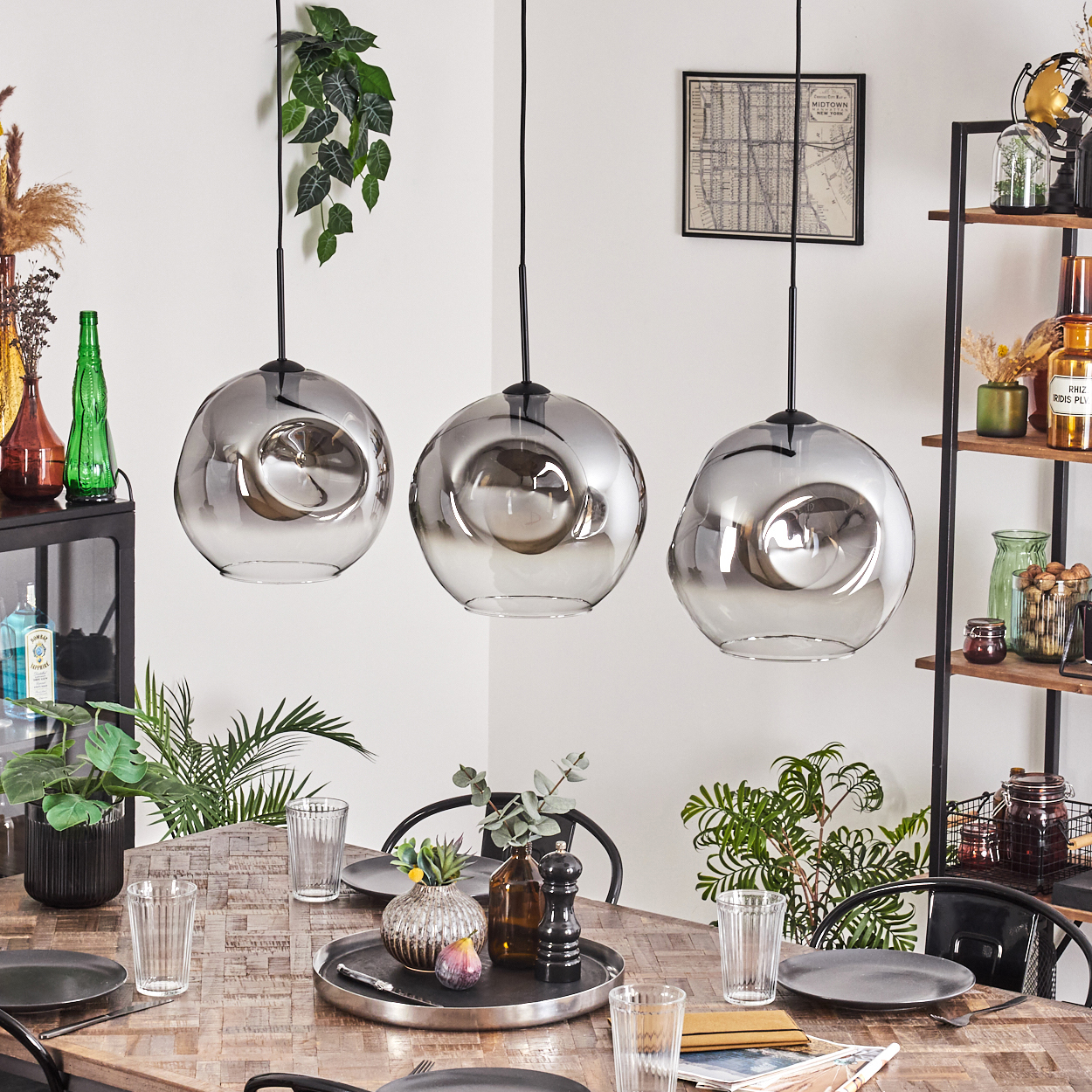Ein Esszimmer mit drei Hängelampen mit Glaskugeln, einem Holztisch und Pflanzen.