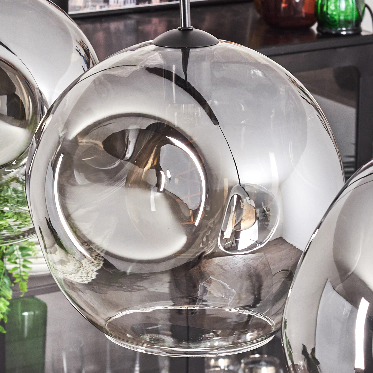 Nahaufnahme einer Ansammlung von Chromkugelleuchten. Sie reflektieren den Raum und haben schwarze Hardware.