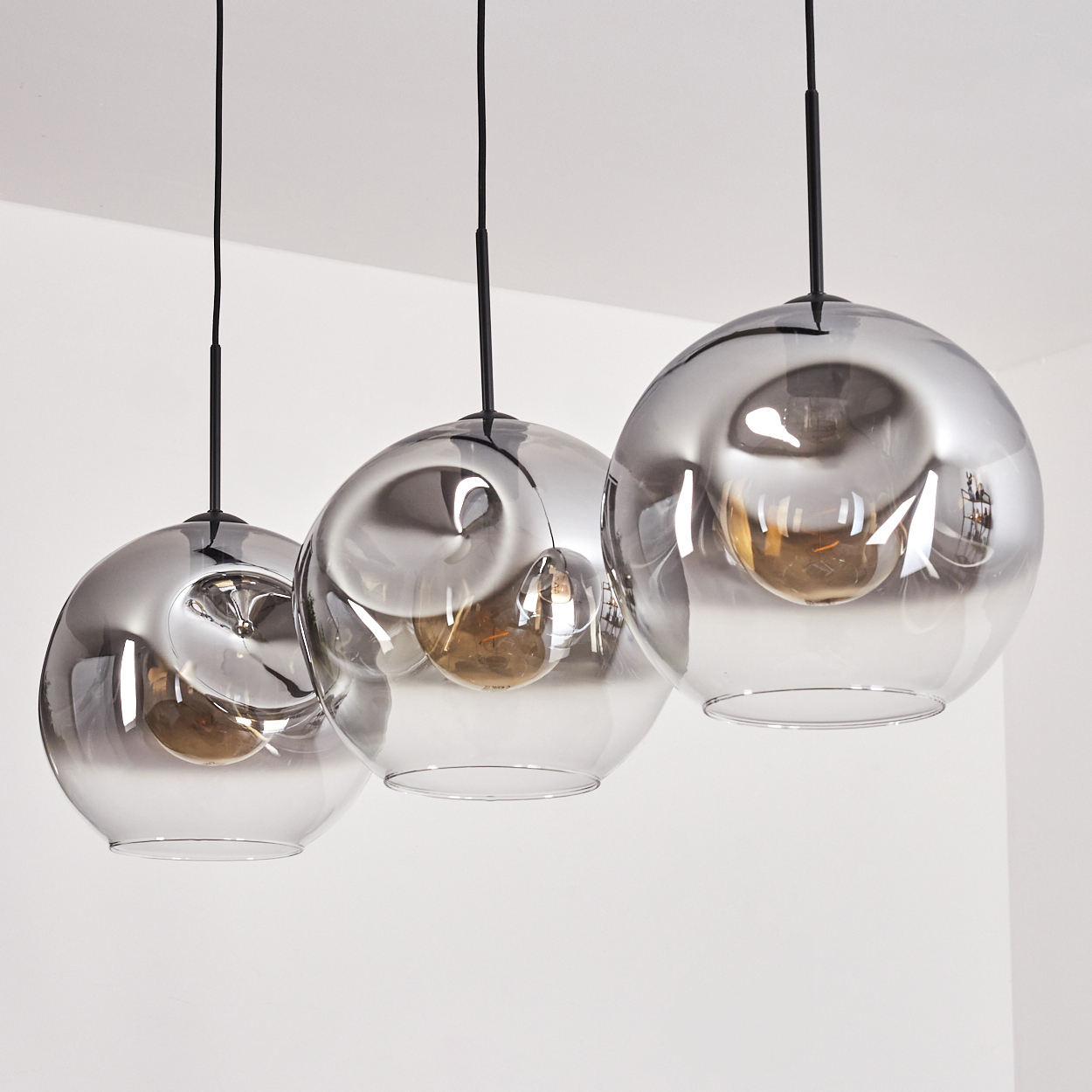 Drei Hängelampen mit Glaskugeln, auf weißem Hintergrund, schlicht und elegant.