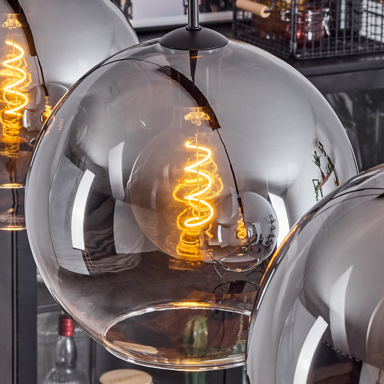 Nahaufnahme von drei kugelförmigen Lampen mit spiralförmigen Glühbirnen. Die Lampen sind reflektierend. Der Hintergrund ist dunkel.