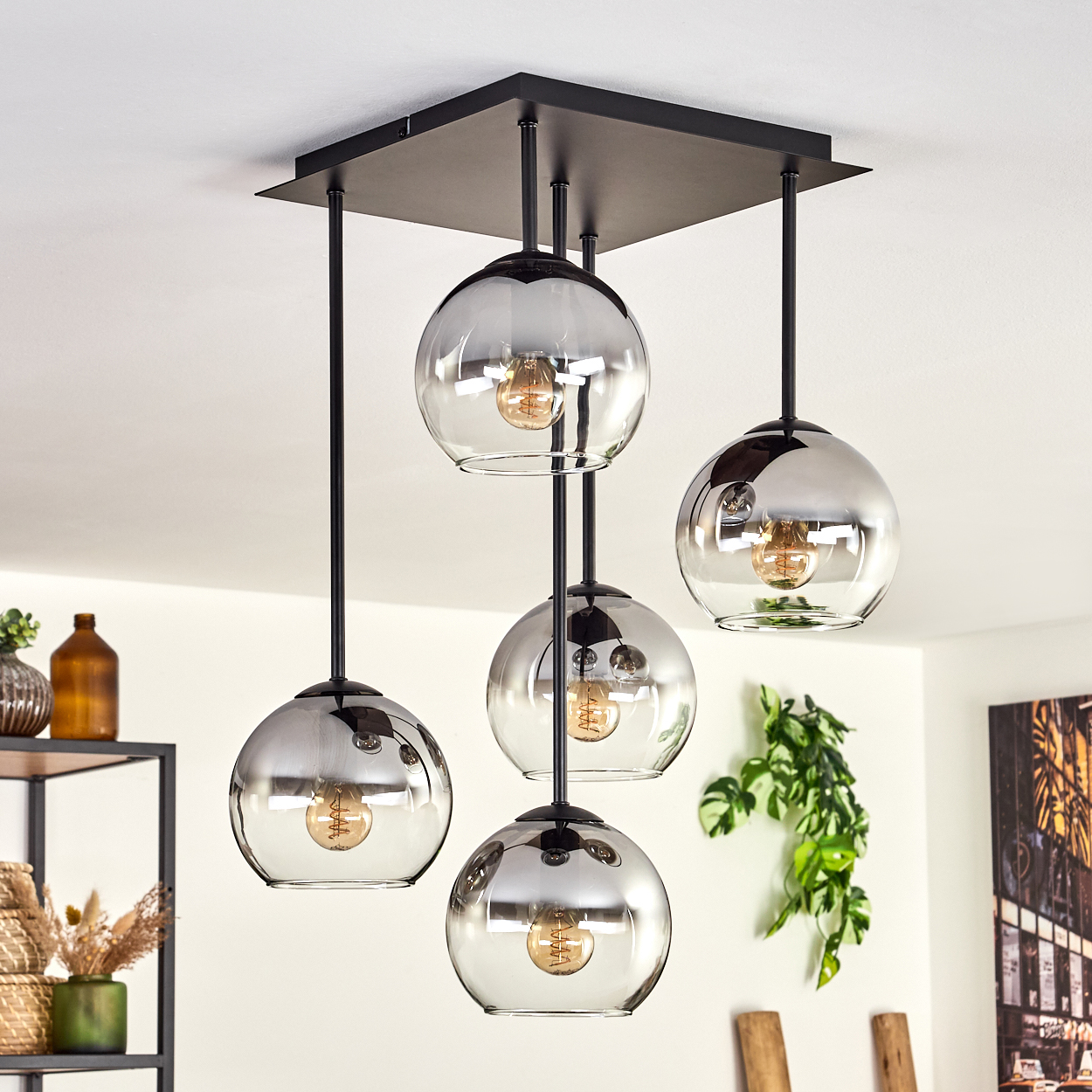 Deckenlampe mit vier Glaskugelschirmen, jede mit einer sichtbaren Glühbirne, von der Decke hängend.