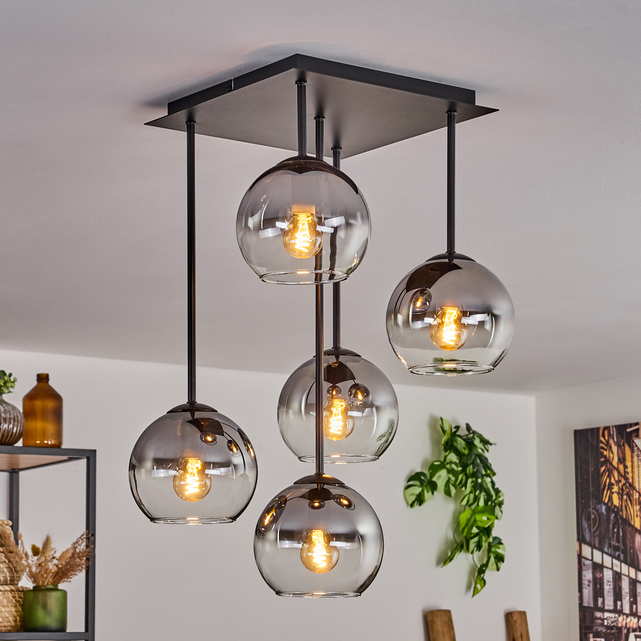 Deckenlampe mit 5 Glaskugelschirmen. Hintergrund ist ein Raum mit einem Gemälde und Pflanzen.