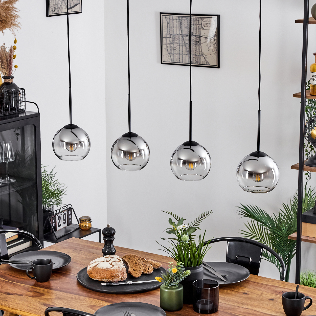 Esszimmer mit Holztisch und vier Hängelampen. Kugelförmige Lampen mit Glühbirnen.