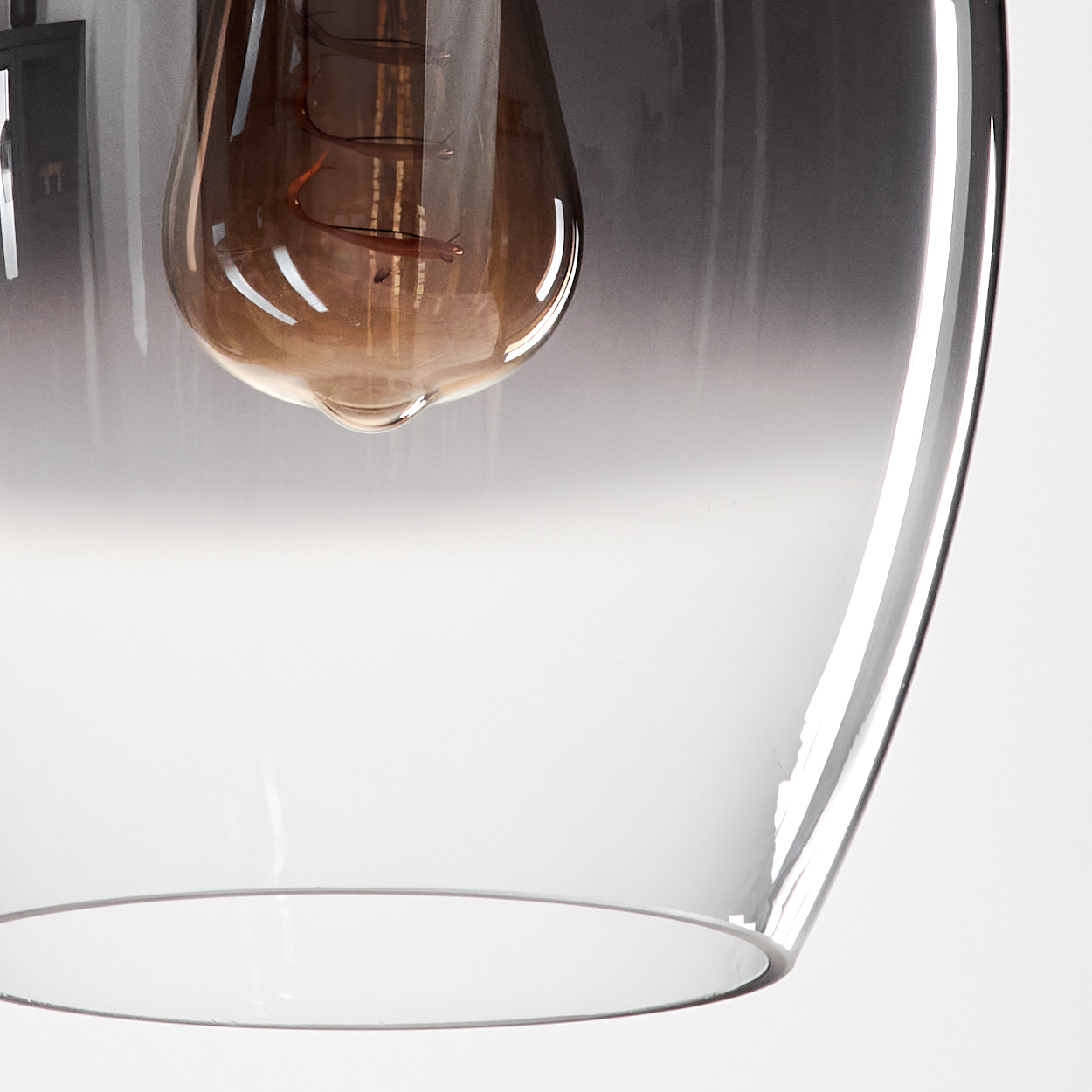 Nahaufnahme einer tropfenförmigen Lampe mit Glühbirne. Die Lampe ist transparent und hängt an einem Draht.