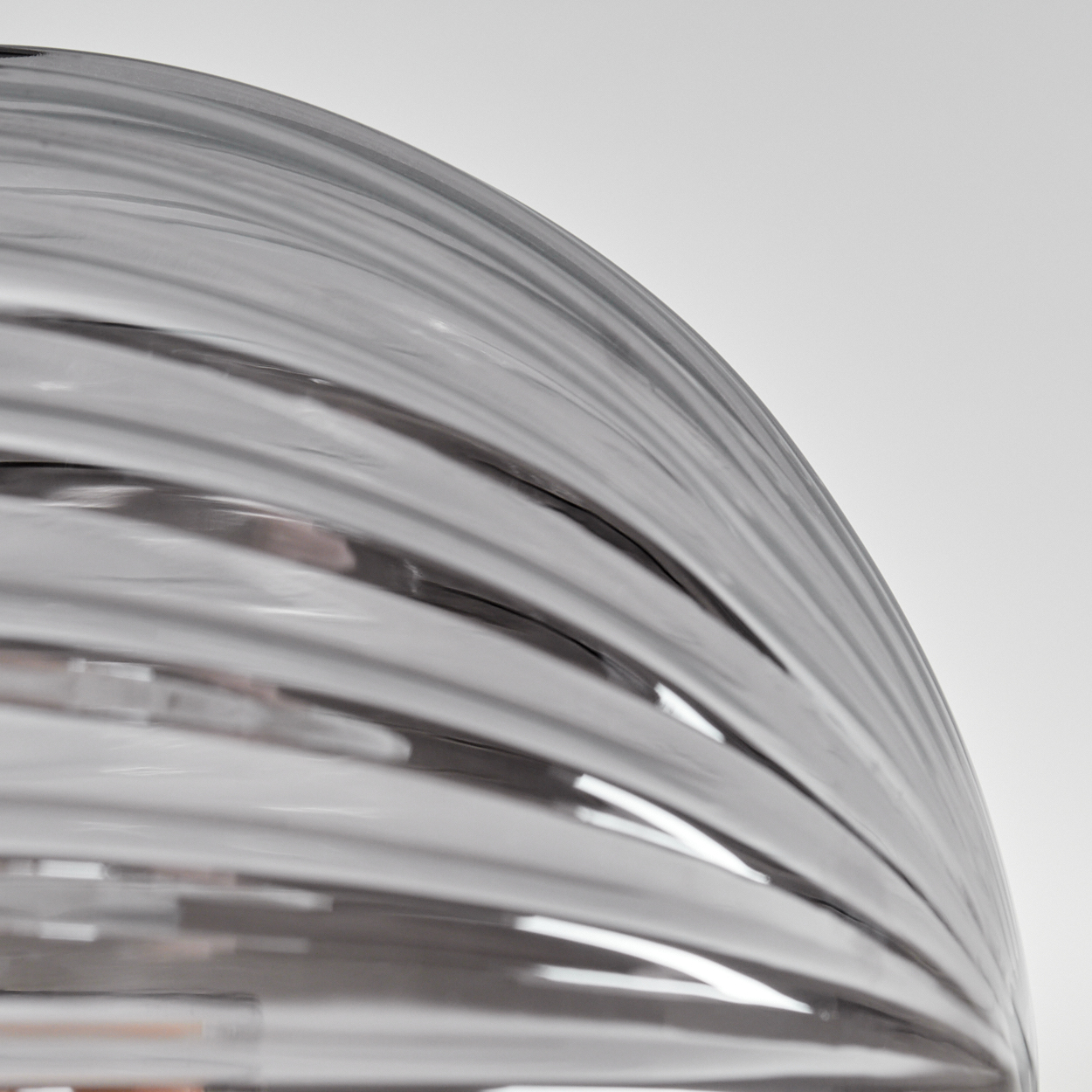 Nahaufnahme einer klaren Glasleuchte mit wellenförmigem Design. Das Glas reflektiert Licht.