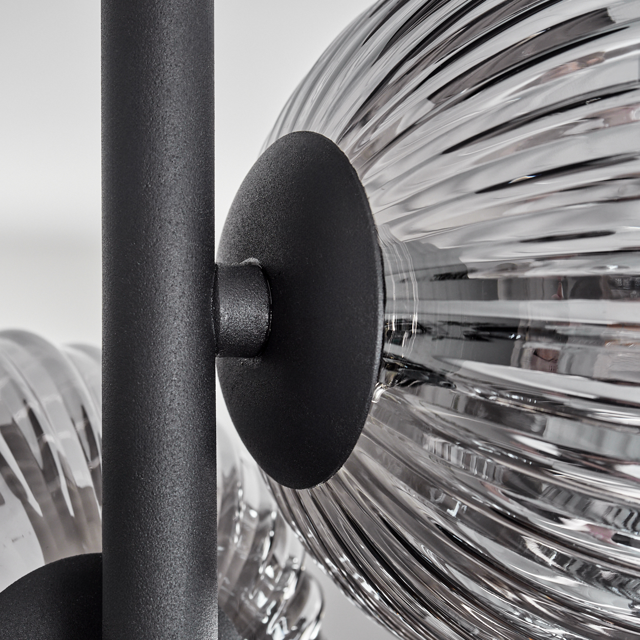 Nahaufnahme einer schwarzen Metallstruktur, die einen Glaskugel mit reflektierender Silberoberfläche hält.