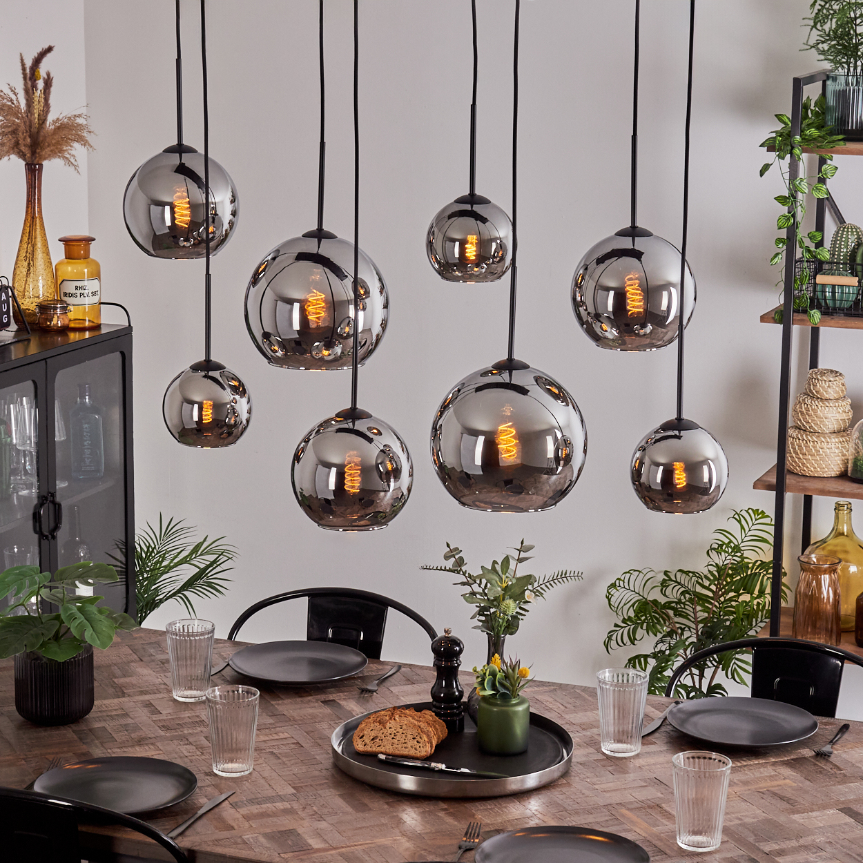 Ein Esszimmer mit acht Pendelleuchten, die über einem Tisch hängen. Eine Vielzahl von Gegenständen befinden sich auf dem Tisch.