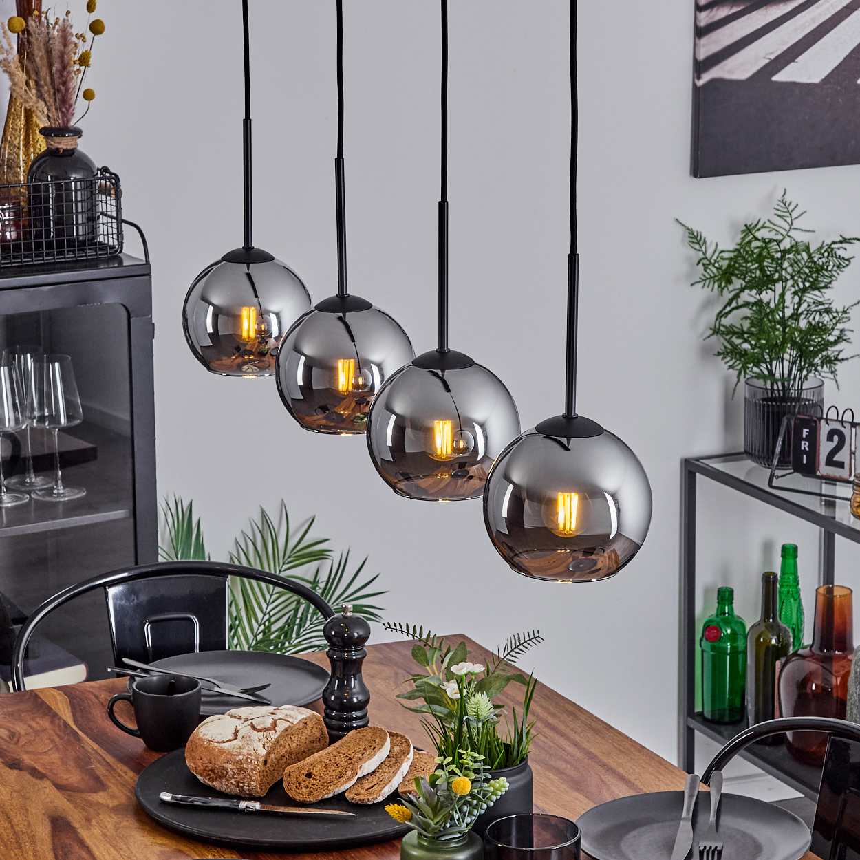 Ein Esszimmer mit einem Holztisch und vier Hängelampen. Teller, Brot und Dekoration sind sichtbar.