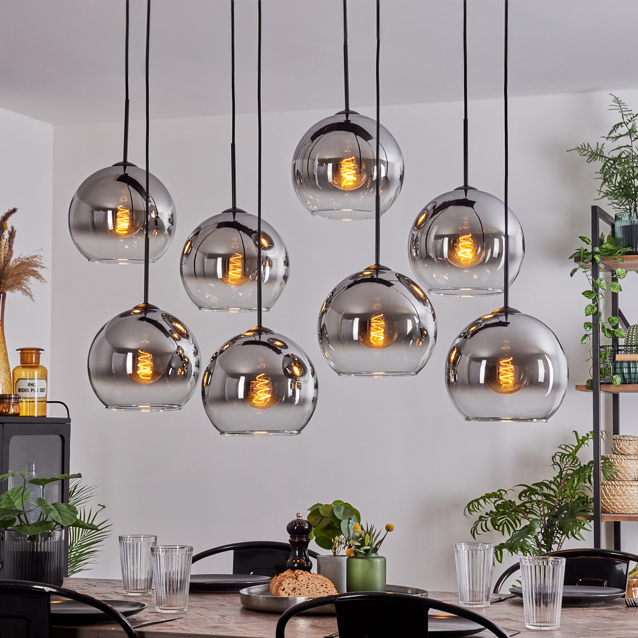 Esszimmer mit acht silbernen Kugelleuchten. Holztisch mit Dekoration, Pflanzen und Gläsern.