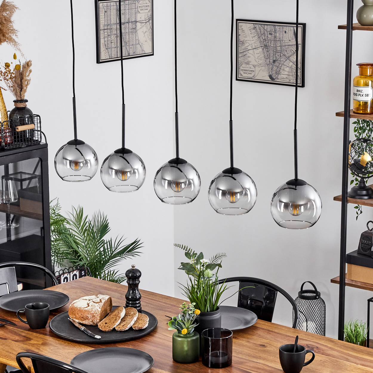 Ein Esszimmer mit Holztisch und fünf silbernen Pendelleuchten.