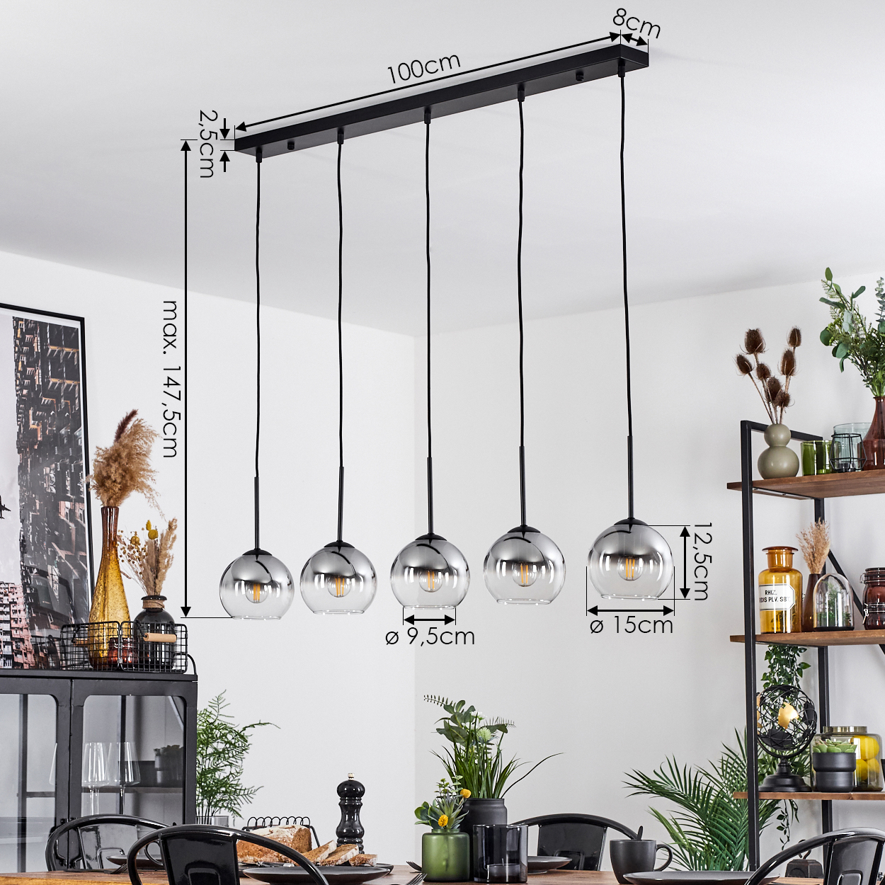 Ein Esszimmer mit Holztisch und fünf silbernen Pendelleuchten mit Messungen.